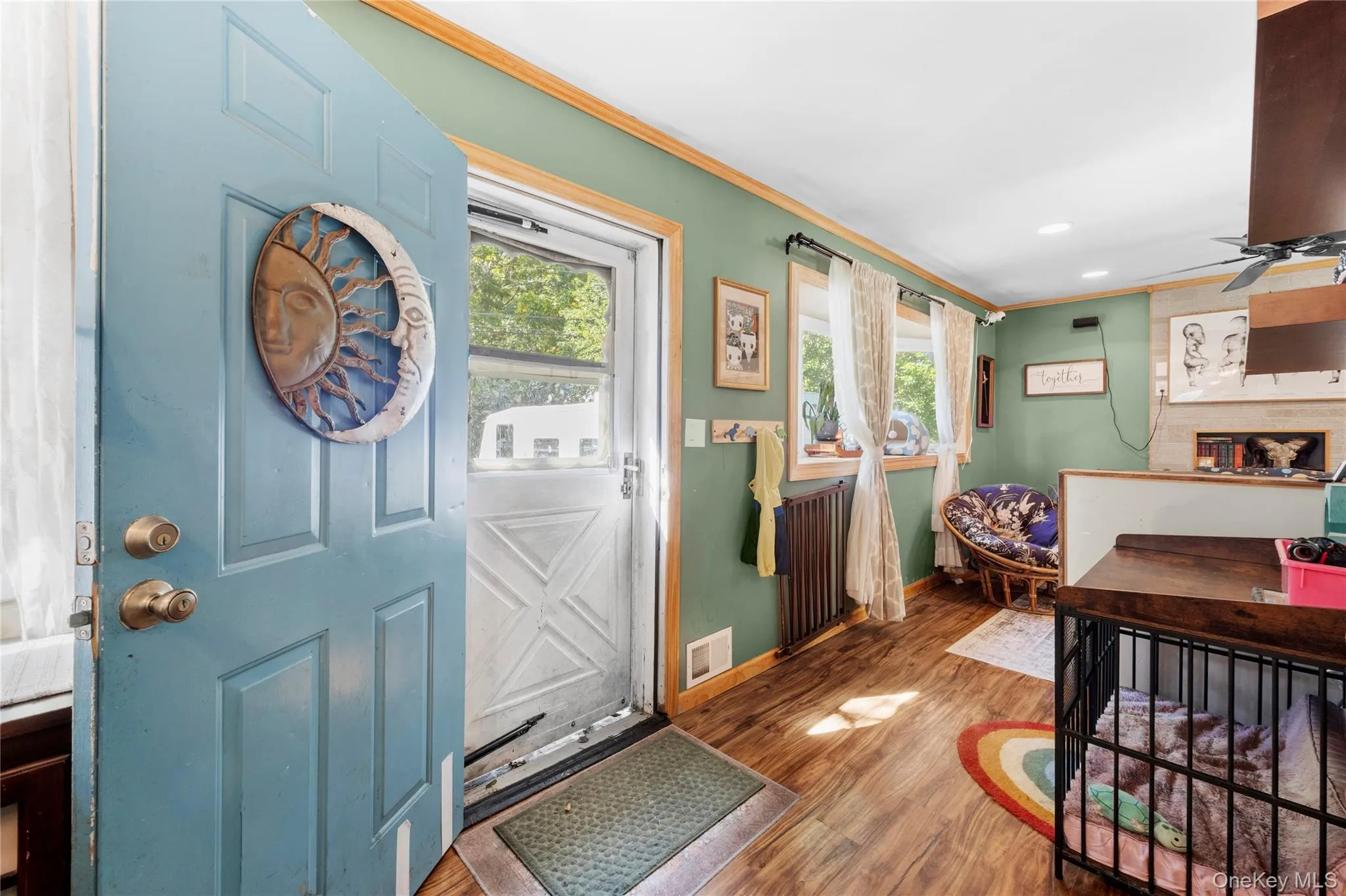 Entryway featuring wood-finish flooring, natural wood crown molding, a white paneled storm door, and a multi-paneled solid wood interior door Entryway featuring wood-finish flooring, natural wood crown molding, a white paneled storm door, and a multi-paneled solid wood interior door