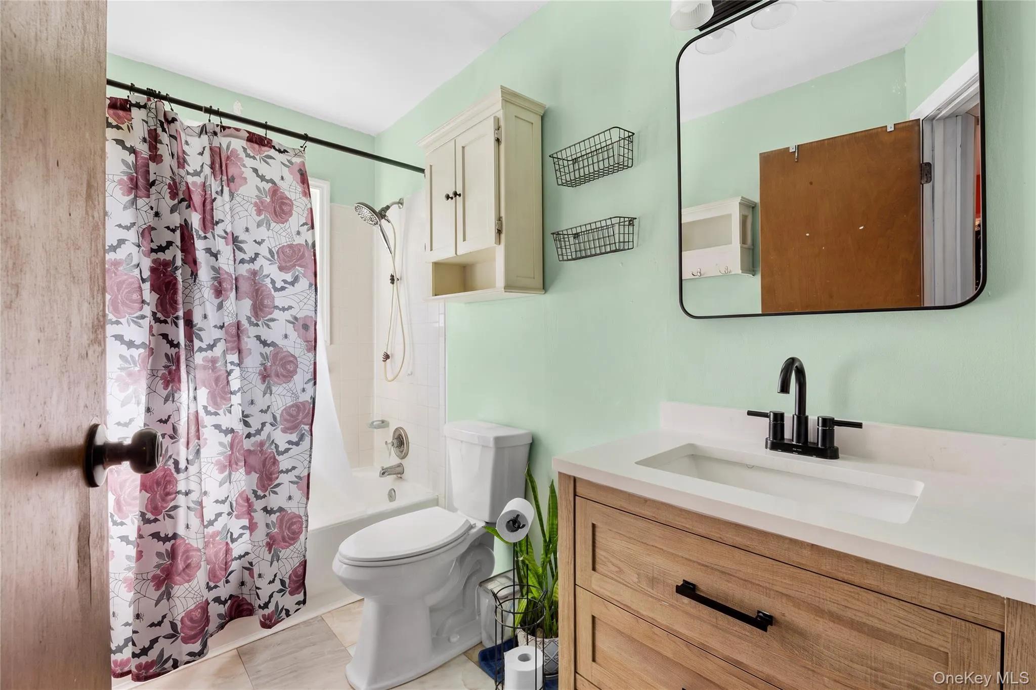 Bathroom featuring a wood-finish vanity with a stone-surface countertop, rectangular undermount sink, matte black faucet, and a wall-mounted rectangular mirror Bathroom featuring a wood-finish vanity with a stone-surface countertop, rectangular undermount sink, matte black faucet, and a wall-mounted rectangular mirror