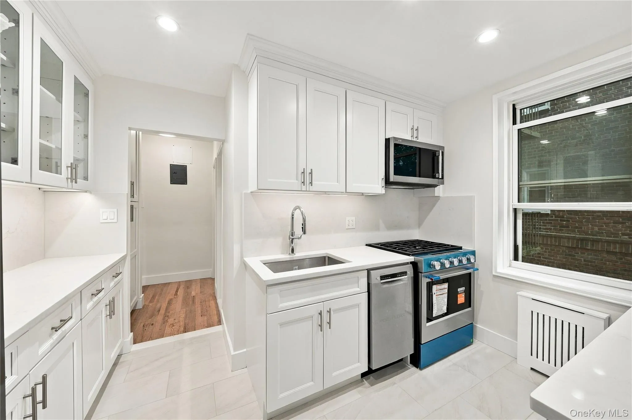 Kitchen featuring white shaker-style cabinetry, solid-surface countertops, stainless steel appliances, and tile flooring Kitchen featuring white shaker-style cabinetry, solid-surface countertops, stainless steel appliances, and tile flooring