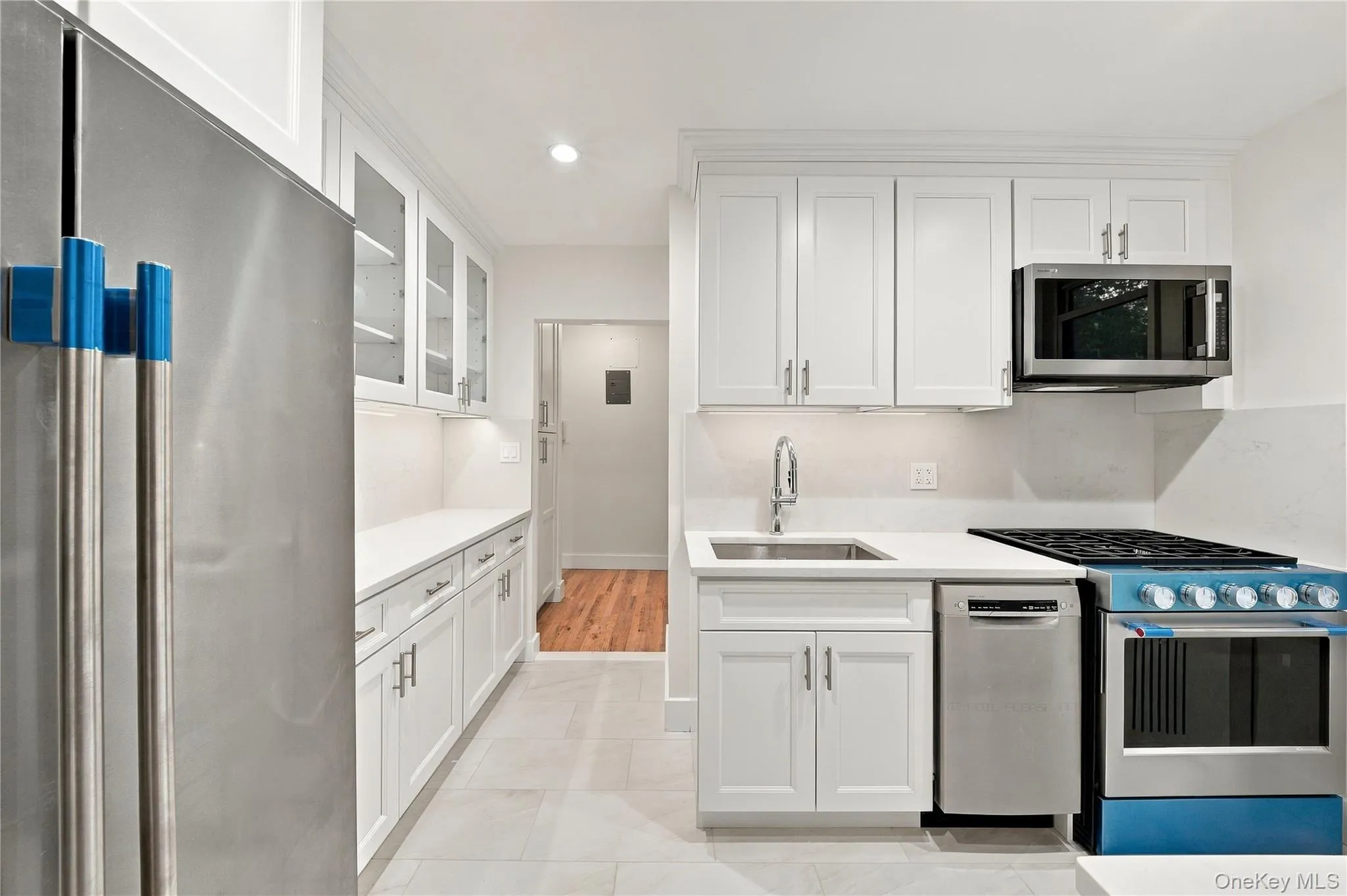 Kitchen featuring white shaker-style cabinetry, solid-surface countertops, stainless steel appliances, a high-arc faucet, and tiled flooring Kitchen featuring white shaker-style cabinetry, solid-surface countertops, stainless steel appliances, a high-arc faucet, and tiled flooring