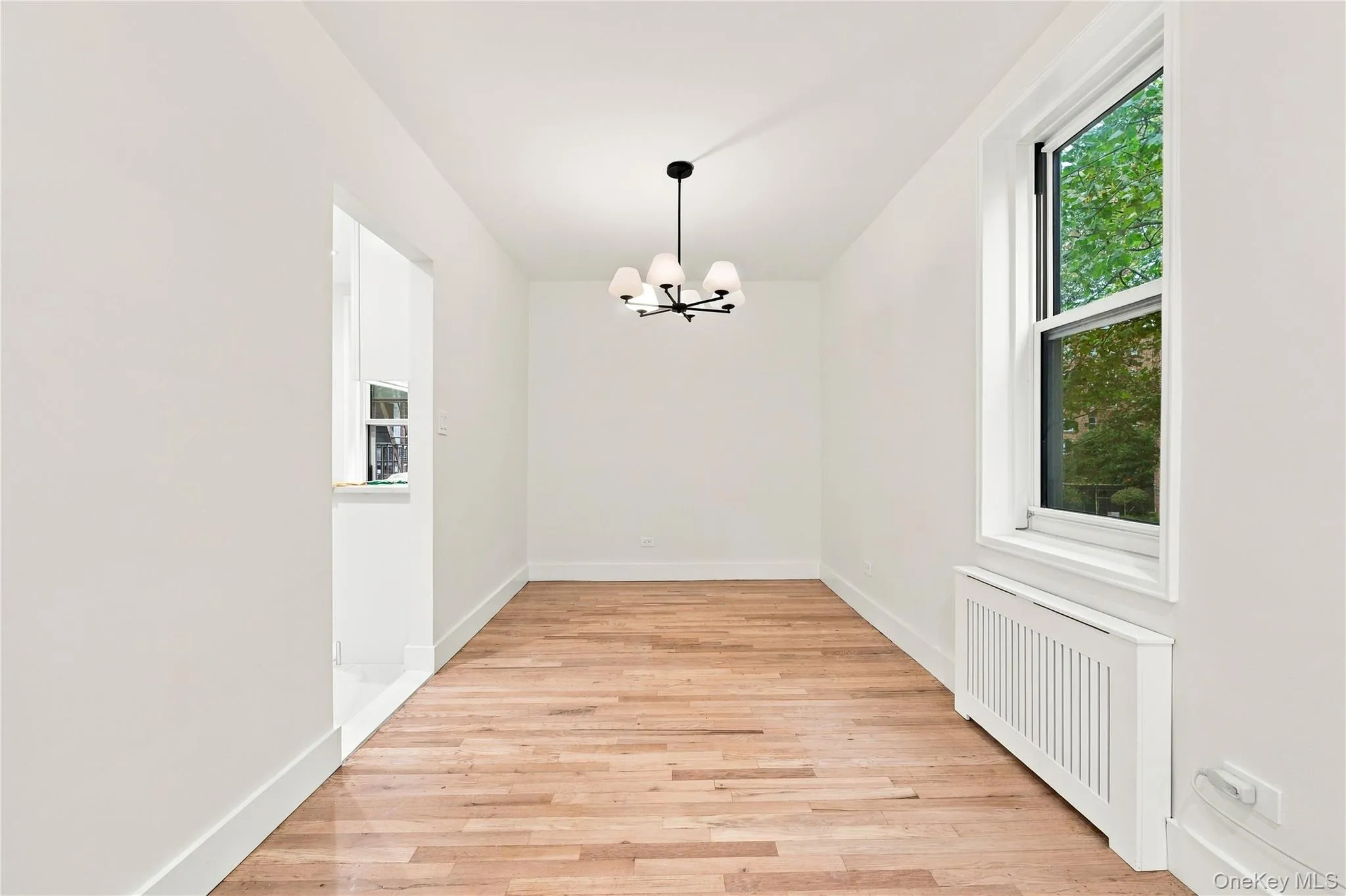 Hardwood flooring, multi-light chandelier, and large window with exterior greenery Hardwood flooring, multi-light chandelier, and large window with exterior greenery