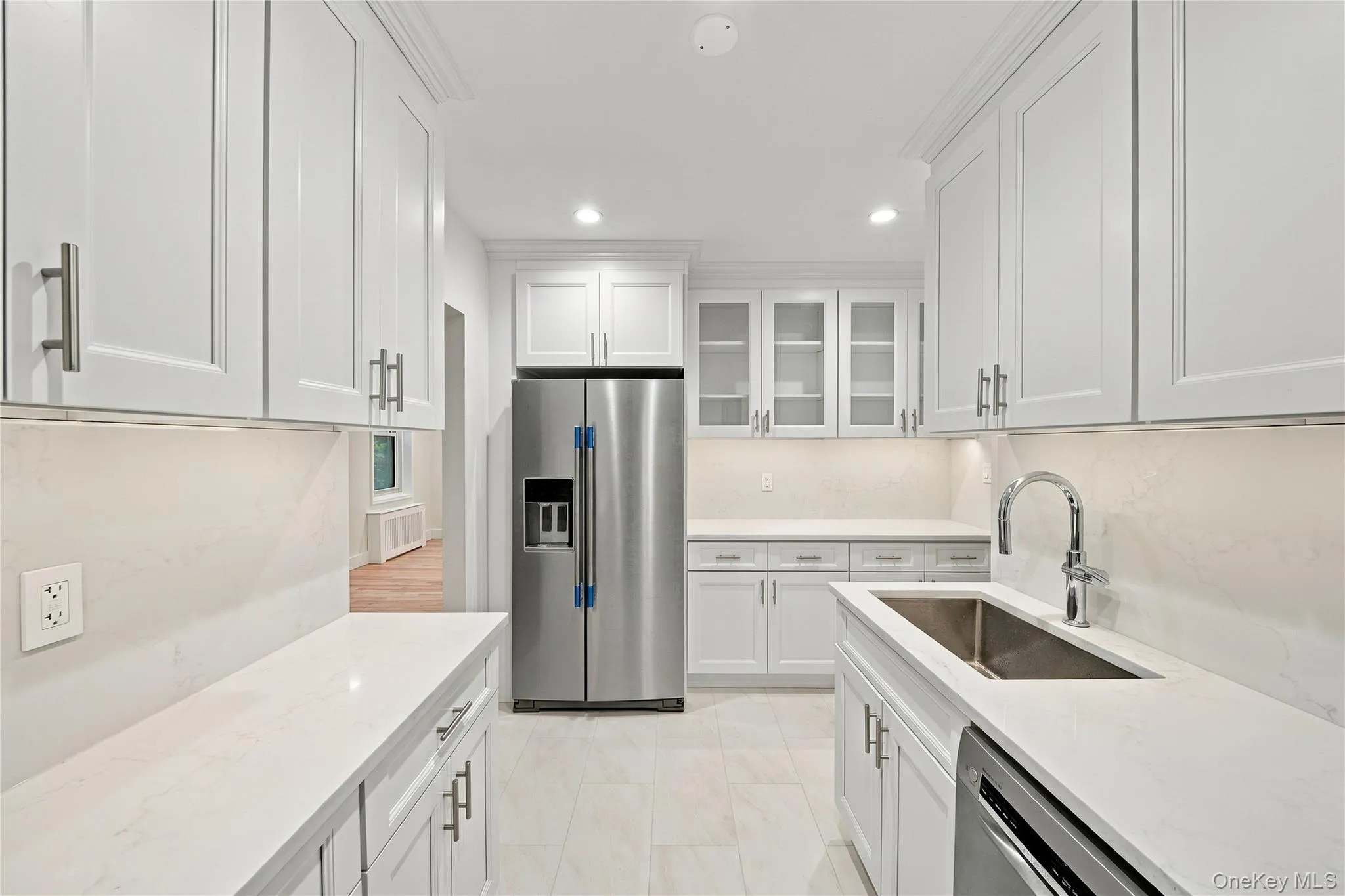 Kitchen featuring white shaker-style cabinetry, quartz countertops, glass-front upper cabinet displays, stainless steel appliances, and a rectangular undermount sink with a high-arc faucet Kitchen featuring white shaker-style cabinetry, quartz countertops, glass-front upper cabinet displays, stainless steel appliances, and a rectangular undermount sink with a high-arc faucet