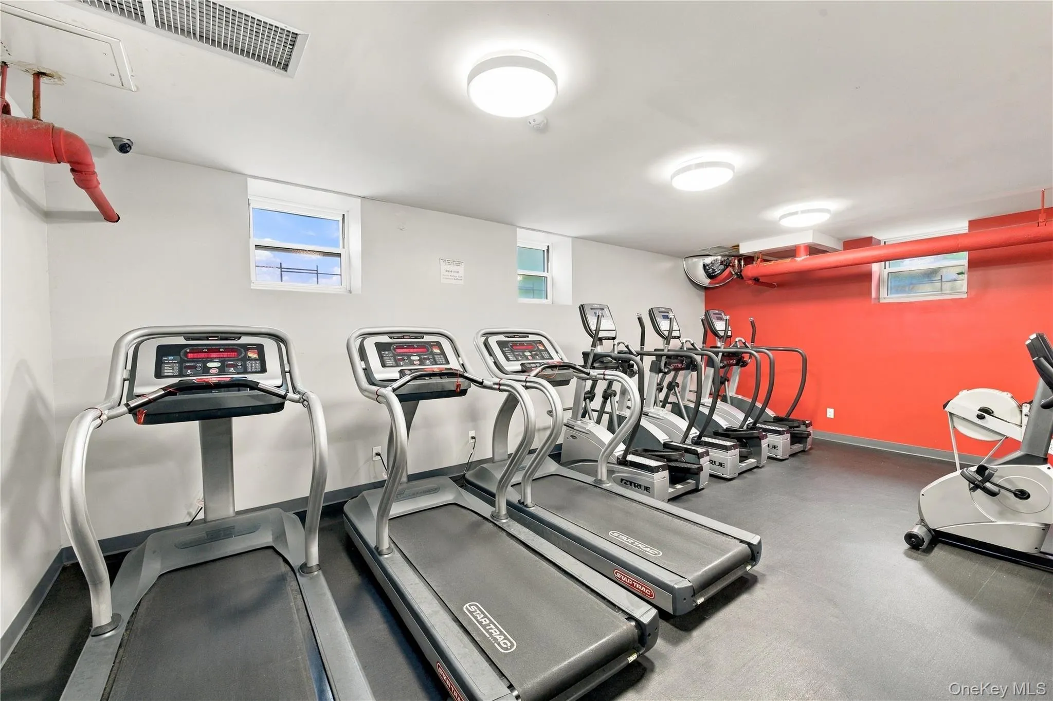 Fitness center featuring rubberized flooring, flush-mount lighting, and three wall-mounted windows Fitness center featuring rubberized flooring, flush-mount lighting, and three wall-mounted windows