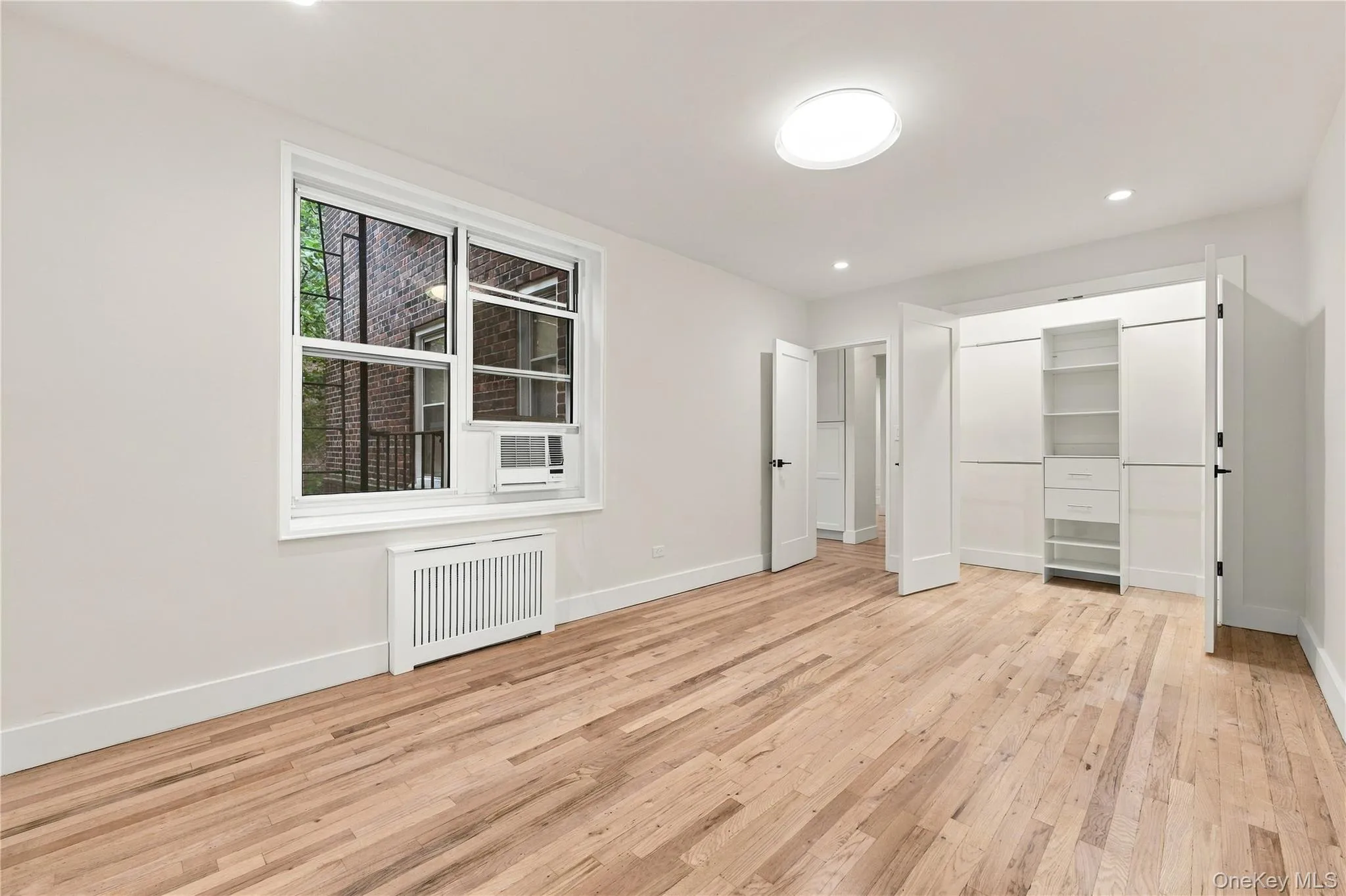Interior featuring wood-finish flooring, recessed lighting, double-door closet with built-in shelving, and a double-hung window Interior featuring wood-finish flooring, recessed lighting, double-door closet with built-in shelving, and a double-hung window