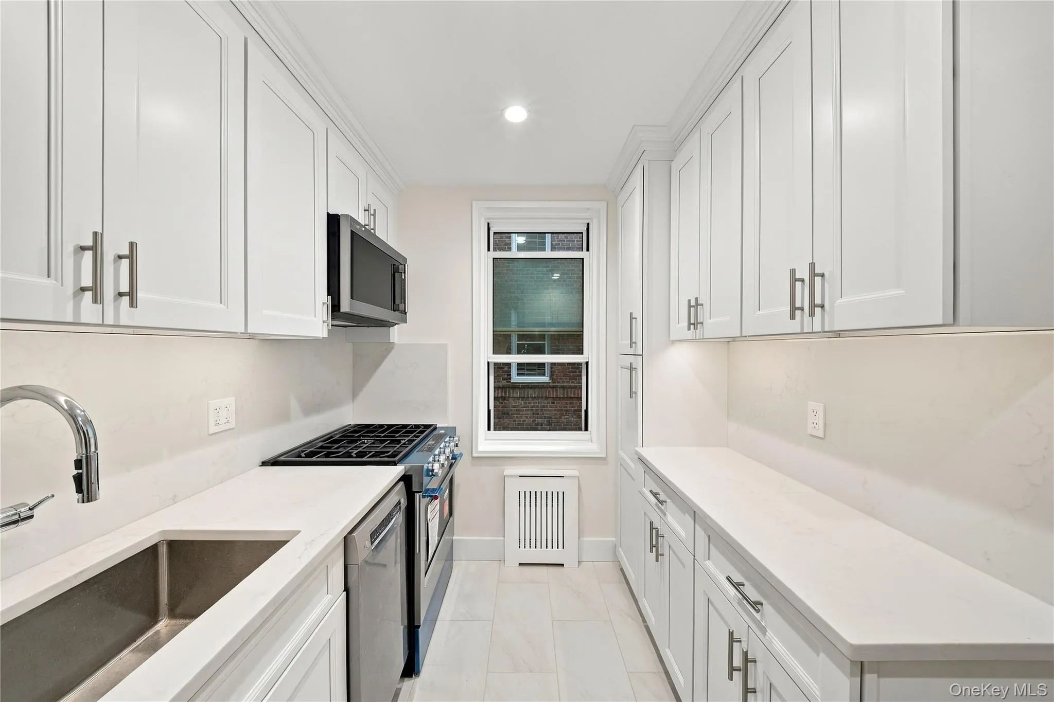 Kitchen featuring white Shaker-style cabinetry, solid-surface countertops, stainless steel appliances, and tile flooring Kitchen featuring white Shaker-style cabinetry, solid-surface countertops, stainless steel appliances, and tile flooring