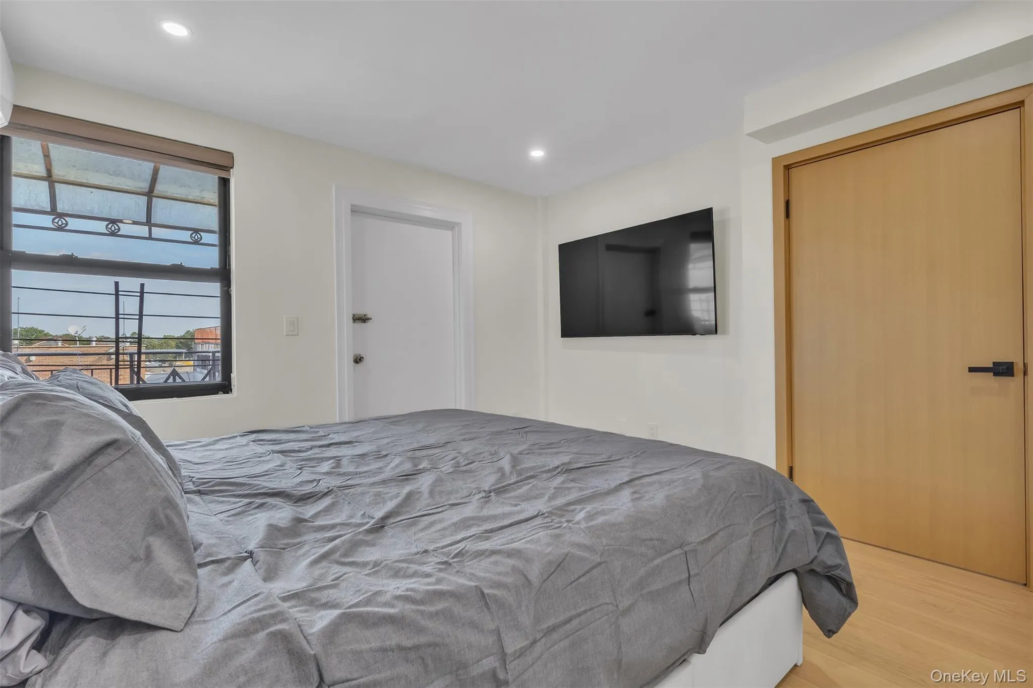 Wood-finish flooring, recessed lighting, solid-core light wood door with matte black hardware, and an expansive window with dark framing Wood-finish flooring, recessed lighting, solid-core light wood door with matte black hardware, and an expansive window with dark framing