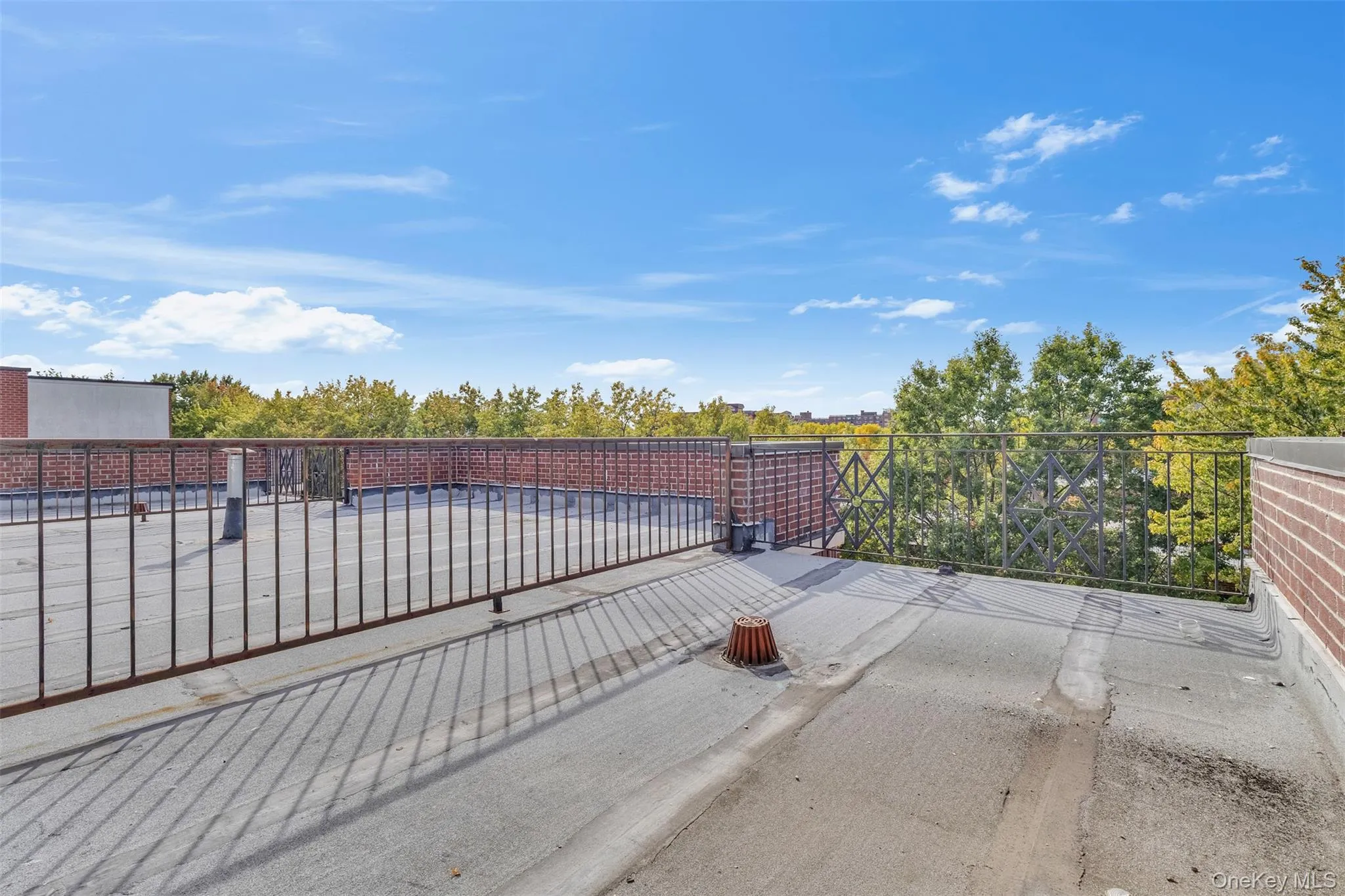 Rooftop terrace featuring a flat surface, low-profile brick parapet walls, and black metal perimeter railings Rooftop terrace featuring a flat surface, low-profile brick parapet walls, and black metal perimeter railings