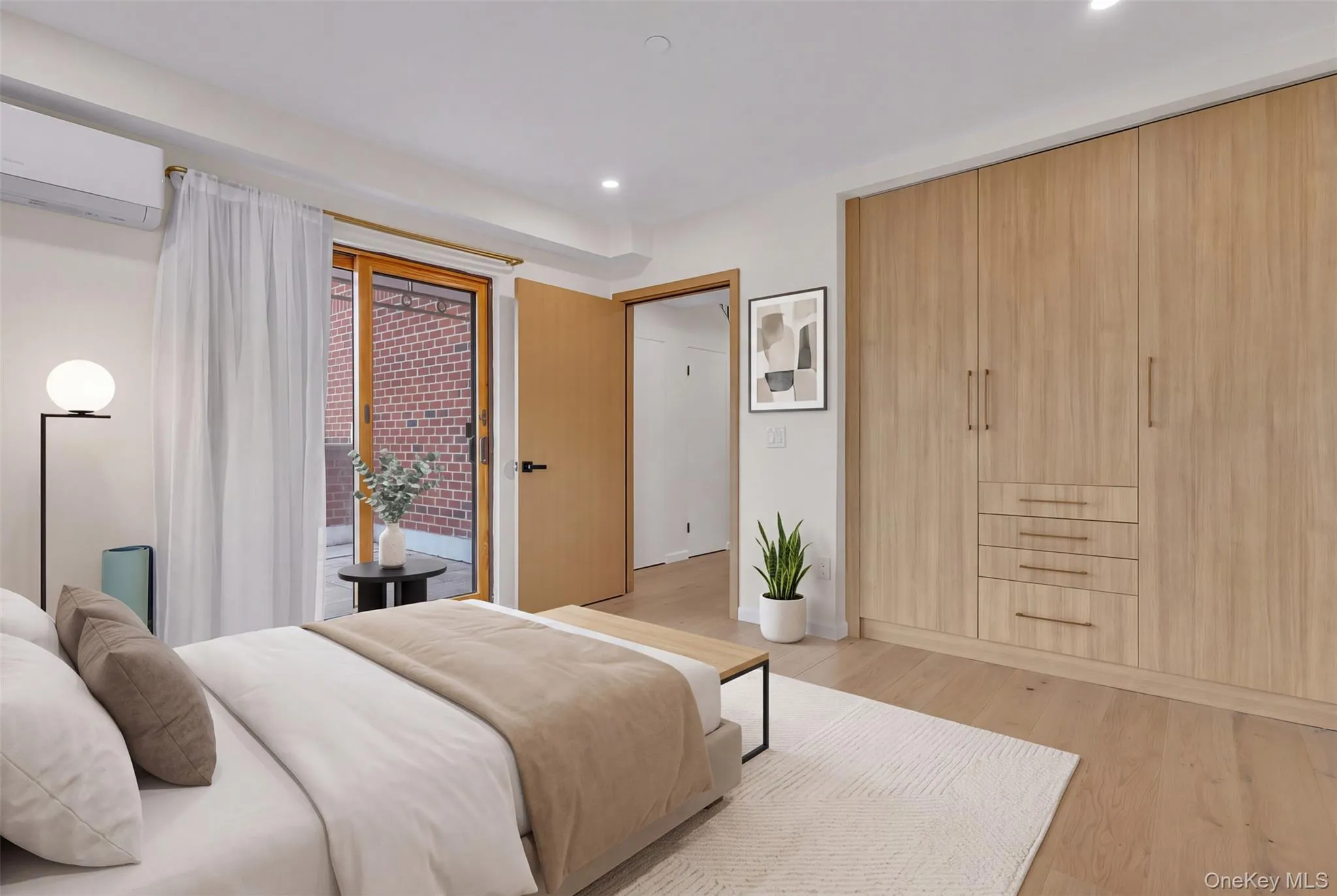 Bedroom featuring floor-to-ceiling custom wood-finish cabinetry with integrated drawers, wood-finish flooring, recessed lighting, and a sliding glass door providing external access Bedroom featuring floor-to-ceiling custom wood-finish cabinetry with integrated drawers, wood-finish flooring, recessed lighting, and a sliding glass door providing external access