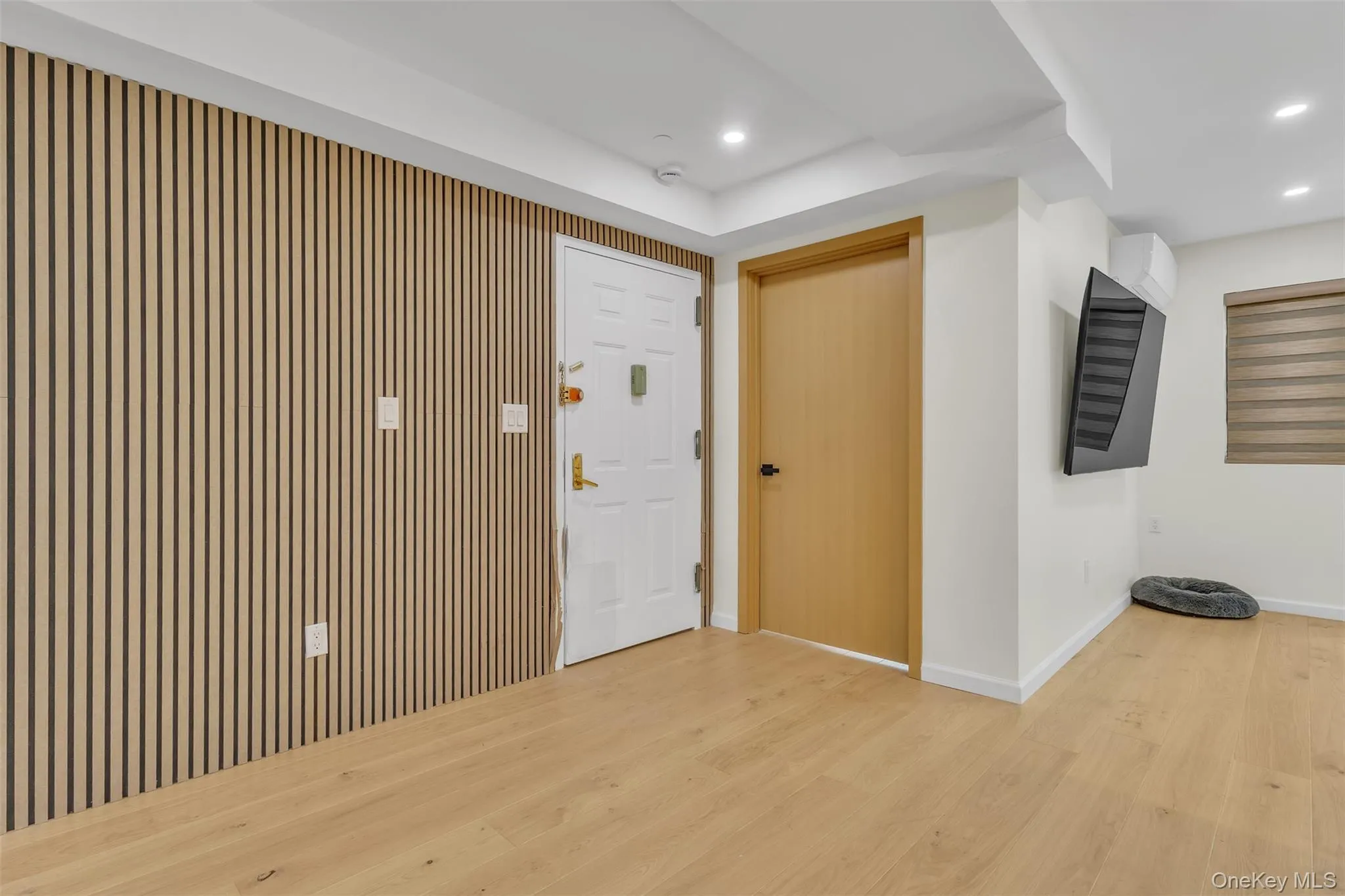 Wood-slat accent wall, light-toned wood-finish flooring, recessed ceiling lighting, and solid-core interior doors Wood-slat accent wall, light-toned wood-finish flooring, recessed ceiling lighting, and solid-core interior doors