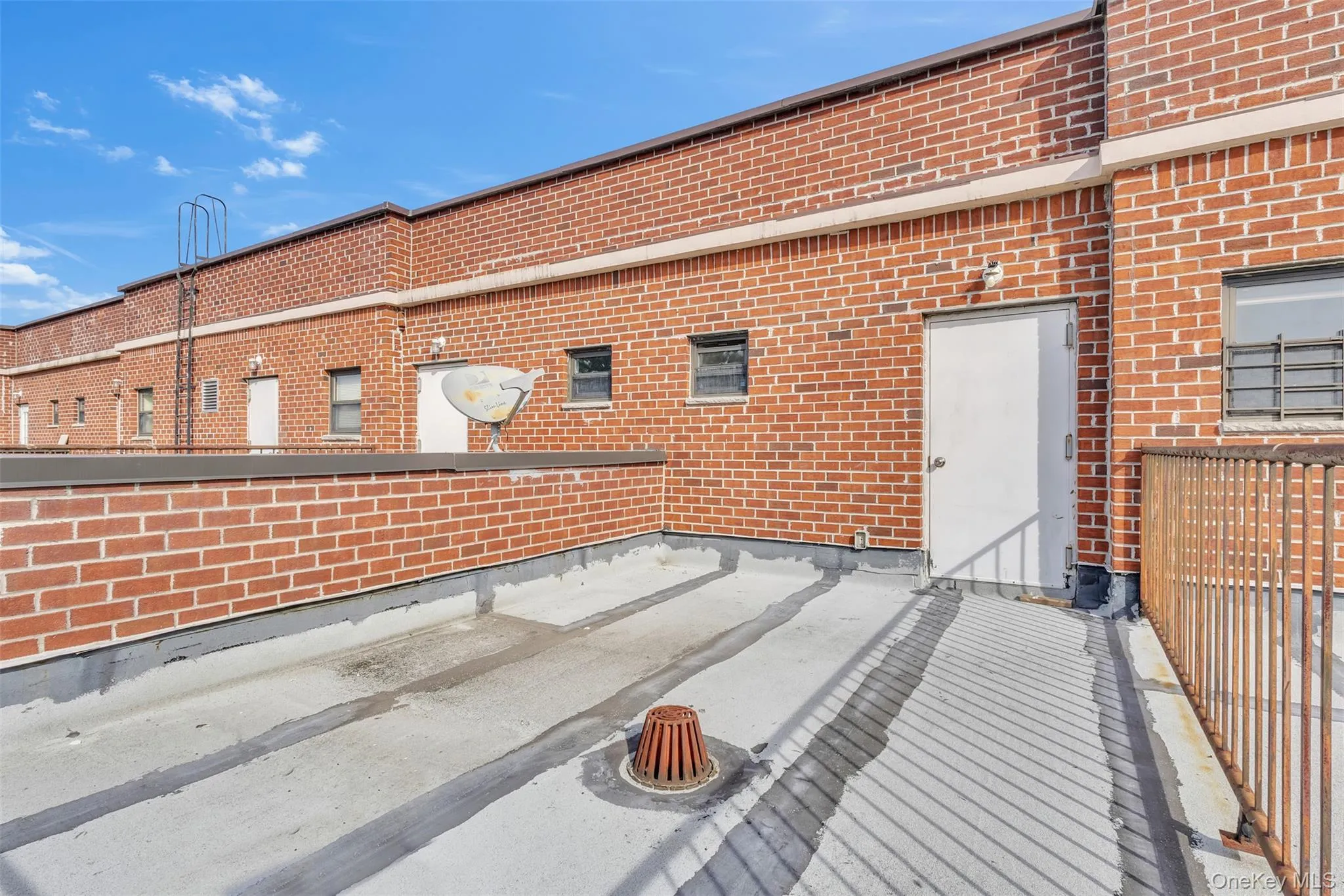 Flat rooftop terrace featuring a brick exterior wall, metal railing, and a drainage access point Flat rooftop terrace featuring a brick exterior wall, metal railing, and a drainage access point