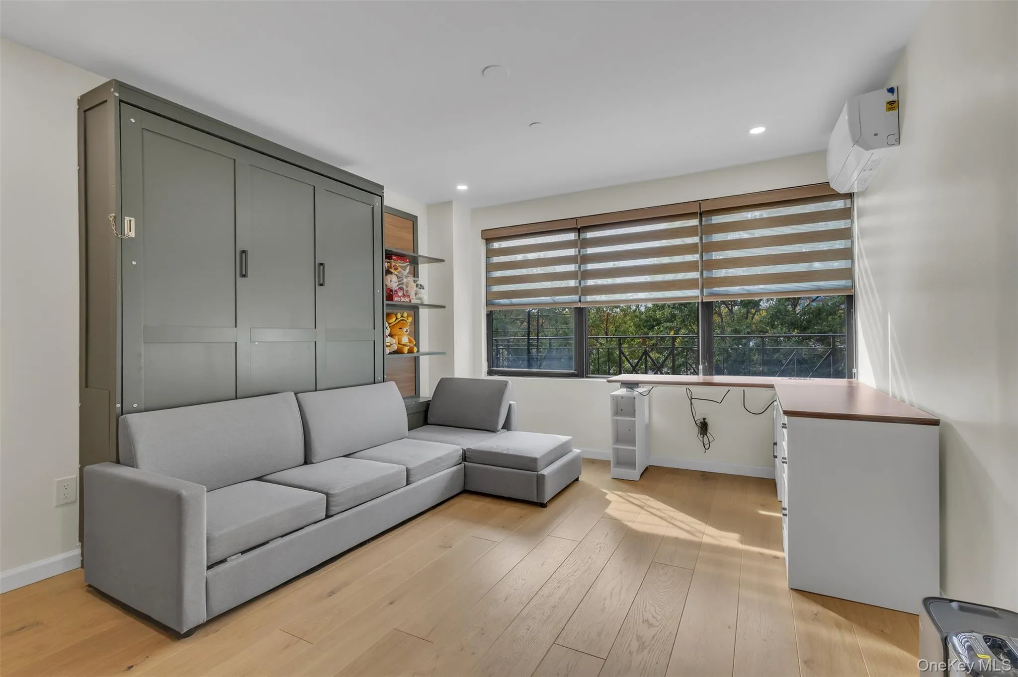 Built-in olive-toned cabinetry, wood-finish flooring, recessed lighting, and wall-mounted climate control unit Built-in olive-toned cabinetry, wood-finish flooring, recessed lighting, and wall-mounted climate control unit