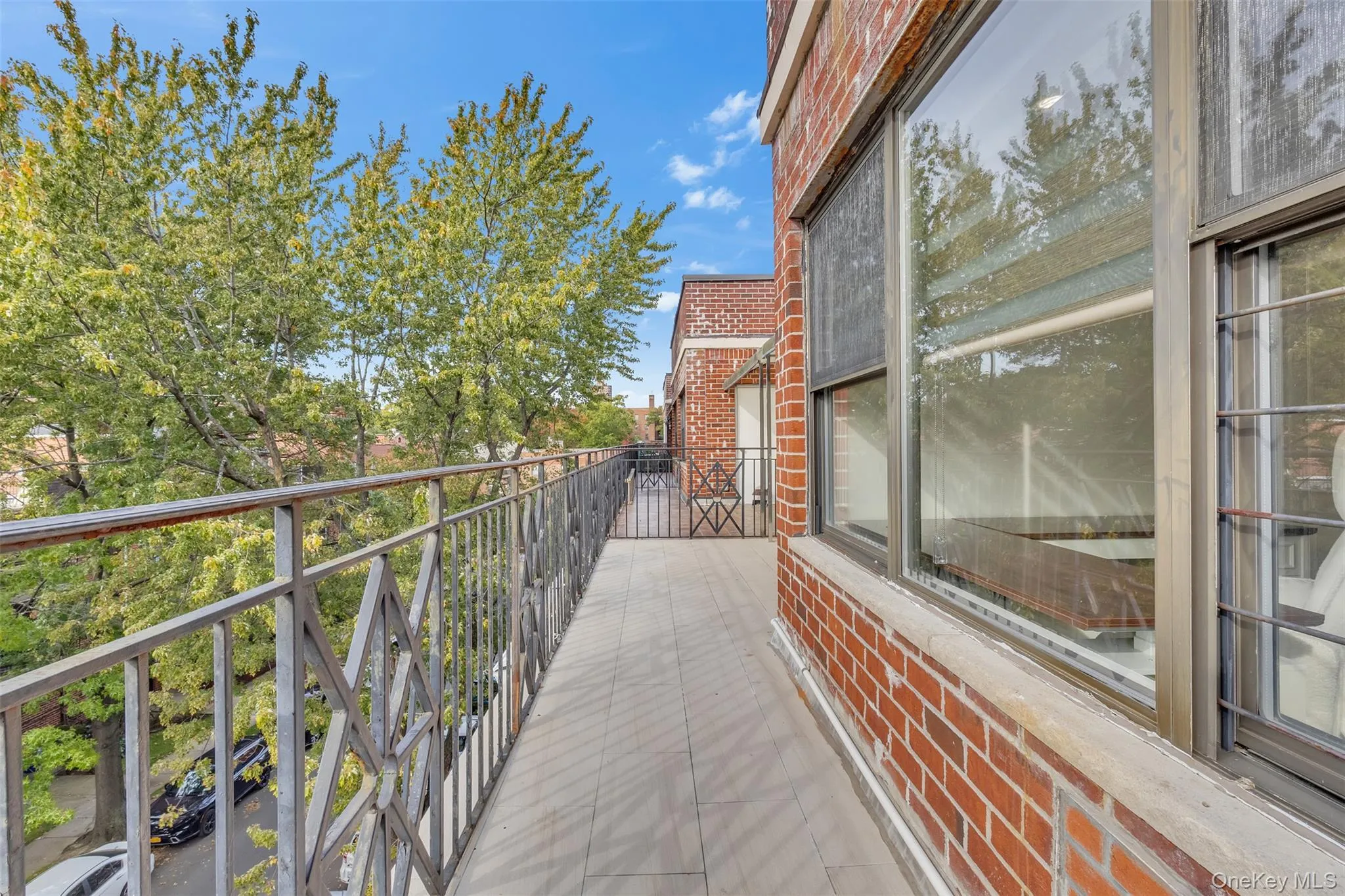 Exterior balcony featuring brick masonry walls, tiled flooring, and decorative metal railings Exterior balcony featuring brick masonry walls, tiled flooring, and decorative metal railings