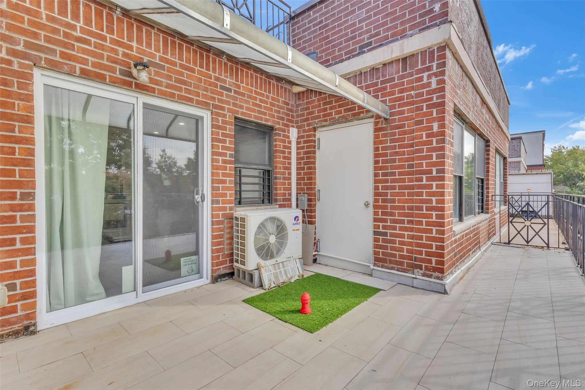 Exterior terrace featuring red brick masonry, tile flooring, a metal railing, and a sliding glass door Exterior terrace featuring red brick masonry, tile flooring, a metal railing, and a sliding glass door