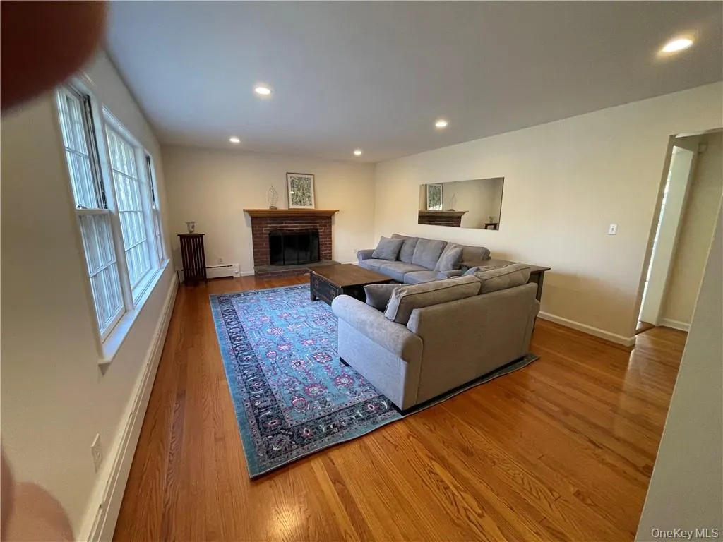 Living room featuring a fireplace, a baseboard heating unit, and hardwood / wood-style floors Living room featuring a fireplace, a baseboard heating unit, and hardwood / wood-style floors