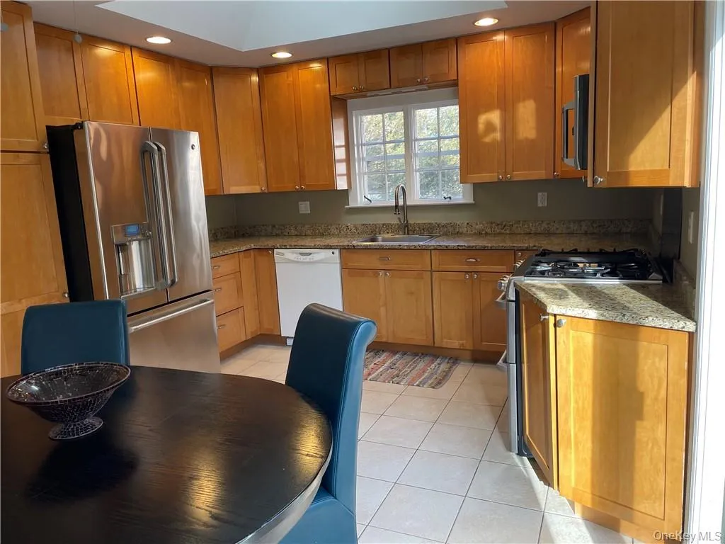 Kitchen featuring light stone counters, light tile patterned floors, stainless steel appliances, and sink Kitchen featuring light stone counters, light tile patterned floors, stainless steel appliances, and sink