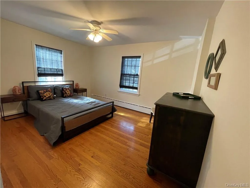 Bedroom featuring a baseboard radiator, ceiling fan, and wood-type flooring Bedroom featuring a baseboard radiator, ceiling fan, and wood-type flooring