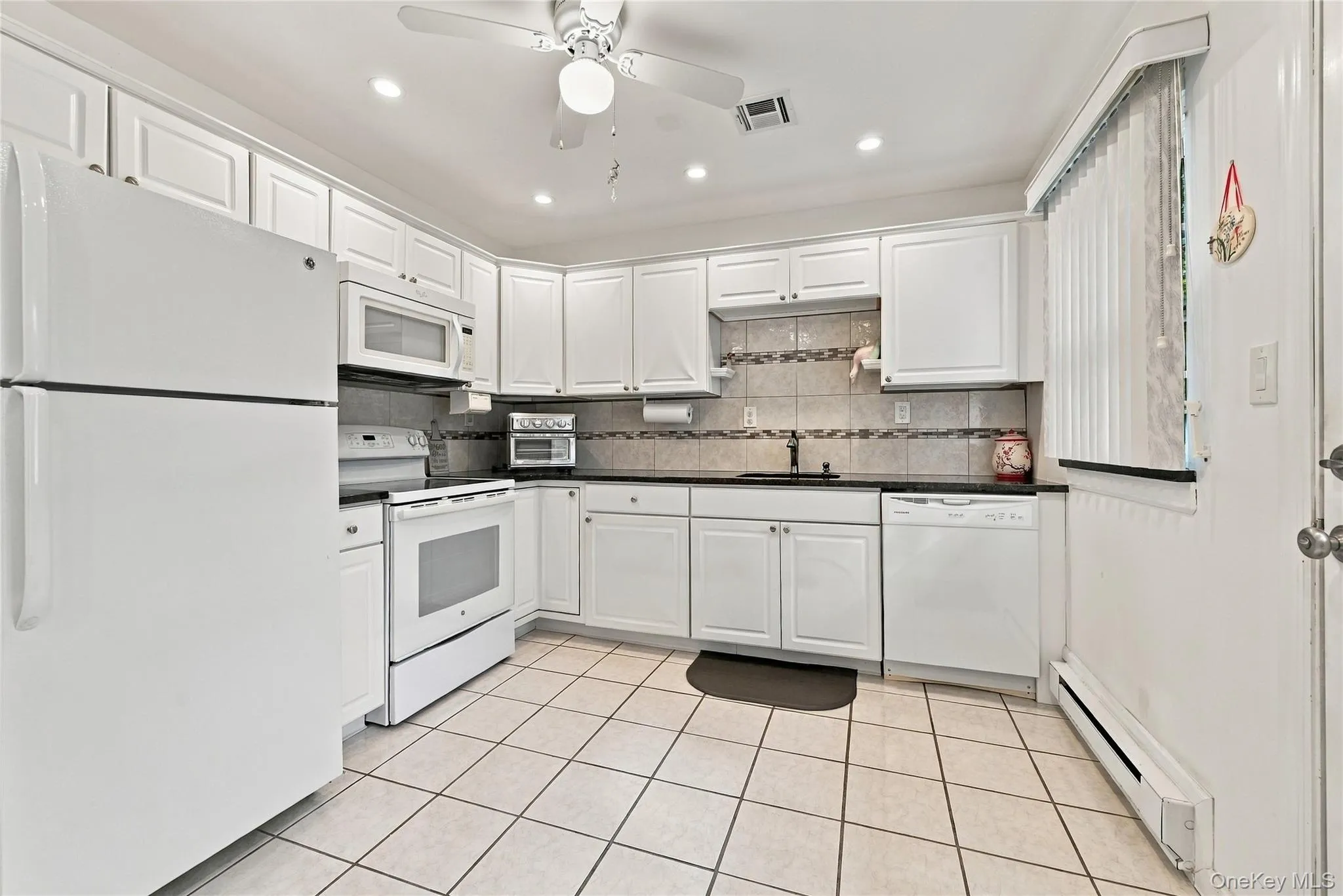 The Stunning, Completely Upgraded Modern Kitchen Offers Walls Of White Raised Panel Cabinetry, Granite Countertops With An Undermount Sink, Tiled Backsplash With Accent Borders, Built In Pantry/Storage, Recessed LED Recessed Lighting, Ceiling Fan, Ceramic Tile Floors, Large Separate Dinette Area & Access To The Attached Garage & The Driveway. The Stunning, Completely Upgraded Modern Kitchen Offers Walls Of White Raised Panel Cabinetry, Granite Countertops With An Undermount Sink, Tiled Backsplash With Accent Borders, Built In Pantry/Storage, Recessed LED Recessed Lighting, Ceiling Fan, Ceramic Tile Floors, Large Separate Dinette Area & Access To The Attached Garage & The Driveway.