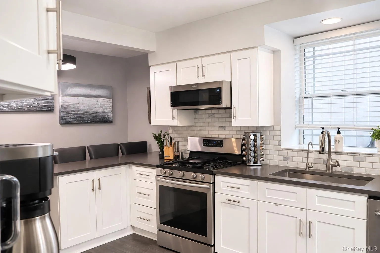Kitchen featuring white shaker-style cabinetry, dark stone countertops, subway tile backsplash, stainless steel gas range with overhead microwave, and a recessed window Kitchen featuring white shaker-style cabinetry, dark stone countertops, subway tile backsplash, stainless steel gas range with overhead microwave, and a recessed window