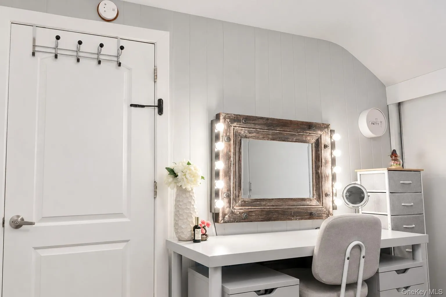 Vertical plank wall paneling and a dedicated vanity station featuring an integrated, wood-frame mirror with perimeter lighting Vertical plank wall paneling and a dedicated vanity station featuring an integrated, wood-frame mirror with perimeter lighting