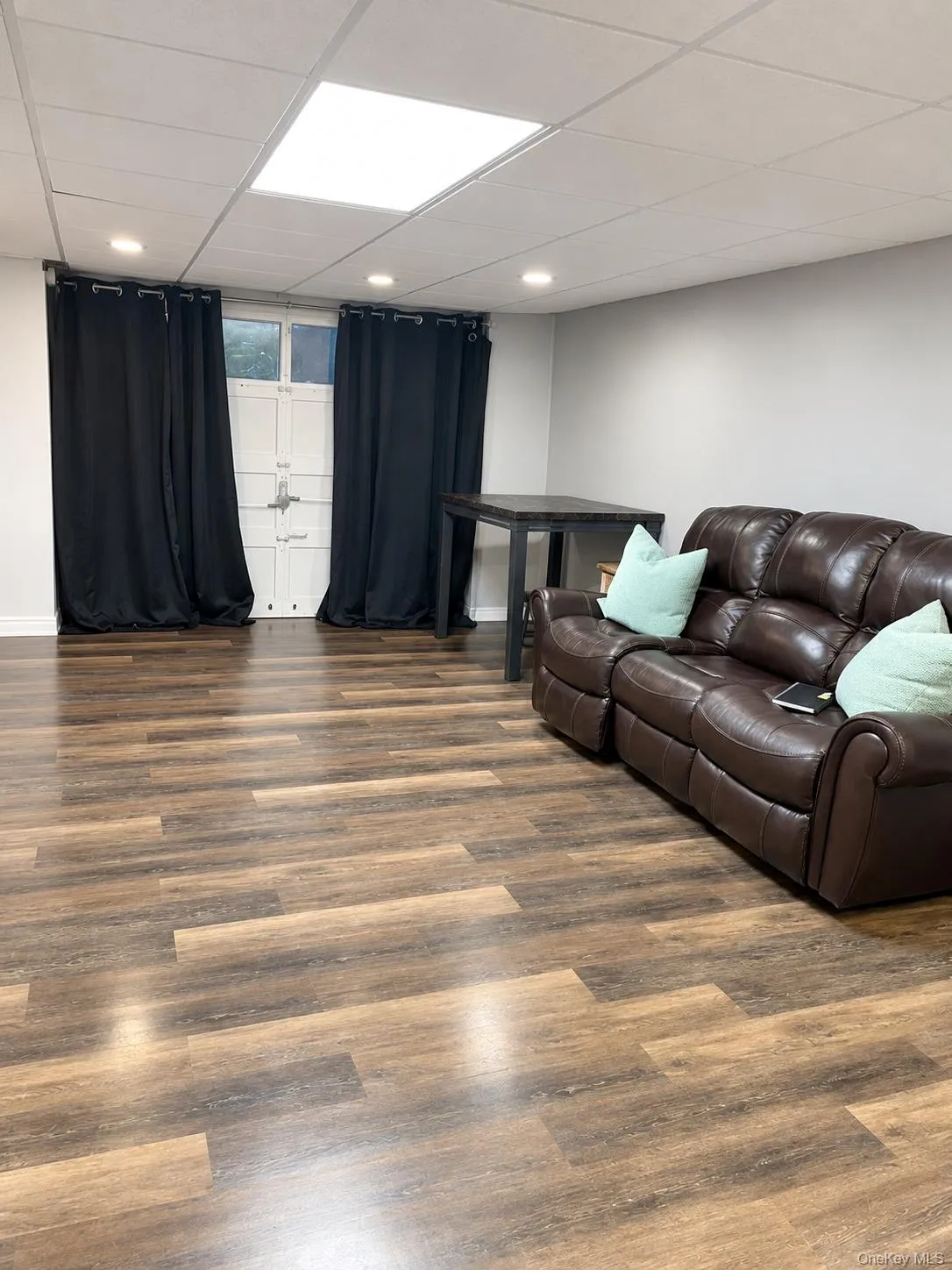 Wood-finish flooring, recessed lighting, and a drop ceiling with a central recessed light panel Wood-finish flooring, recessed lighting, and a drop ceiling with a central recessed light panel