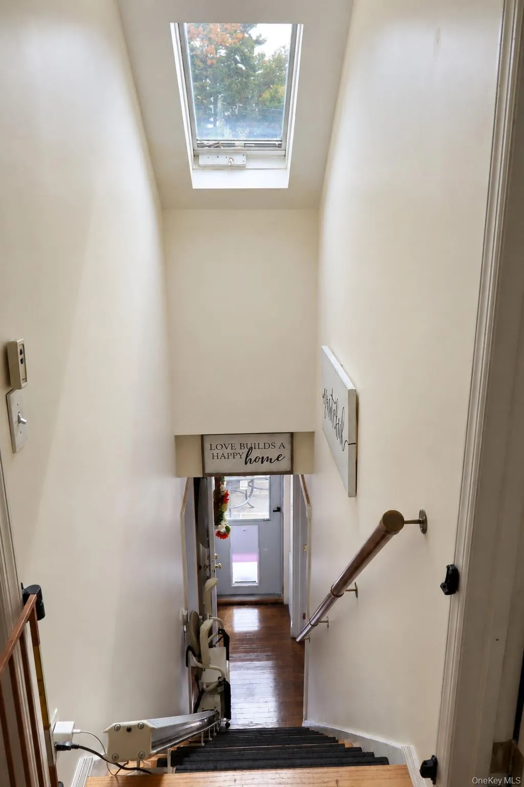 Staircase featuring a skylight and a wall-mounted metal handrail Staircase featuring a skylight and a wall-mounted metal handrail
