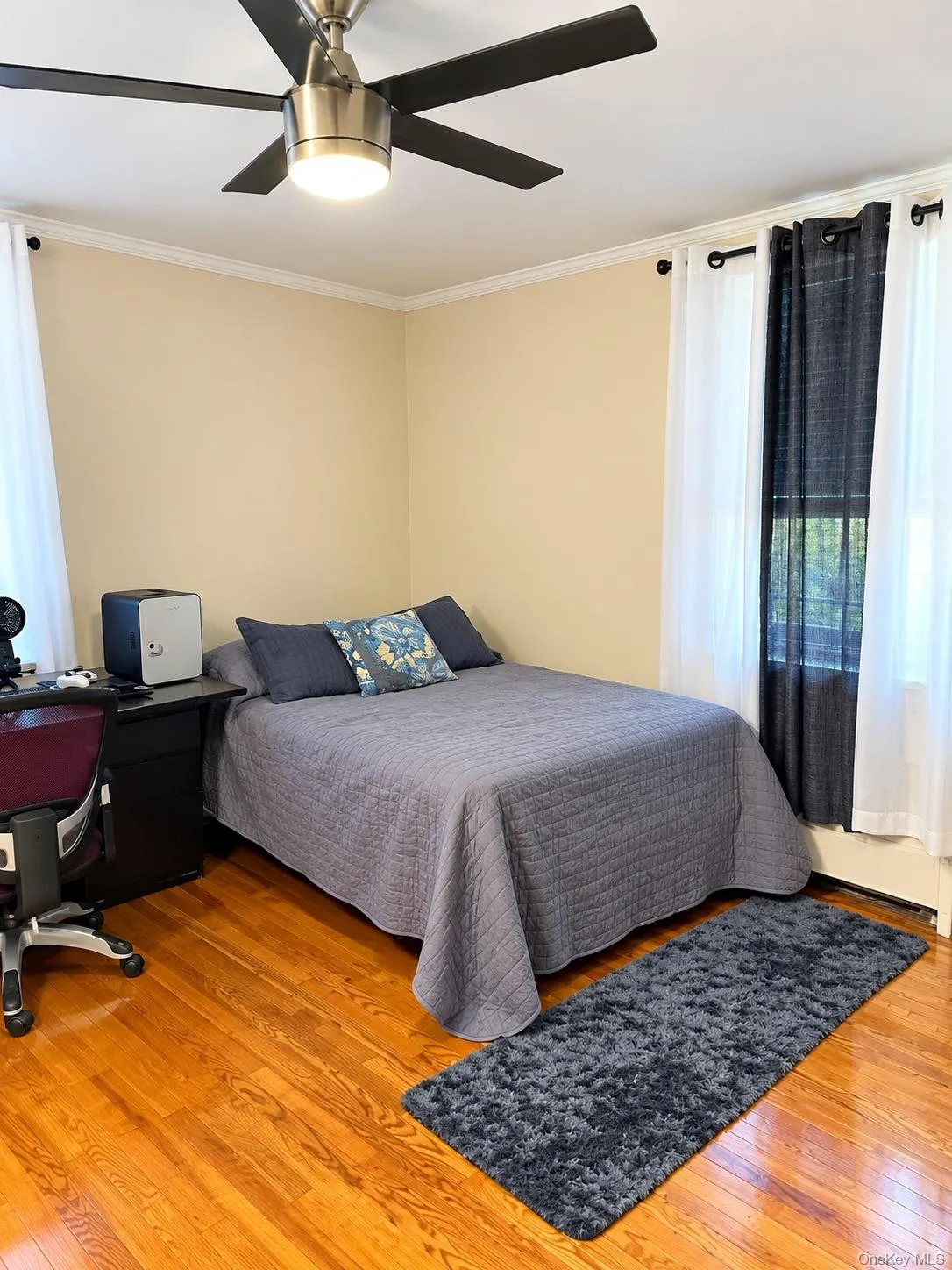 Room featuring wood-finish flooring, a stainless steel ceiling fan with integrated lighting, and crown molding Room featuring wood-finish flooring, a stainless steel ceiling fan with integrated lighting, and crown molding