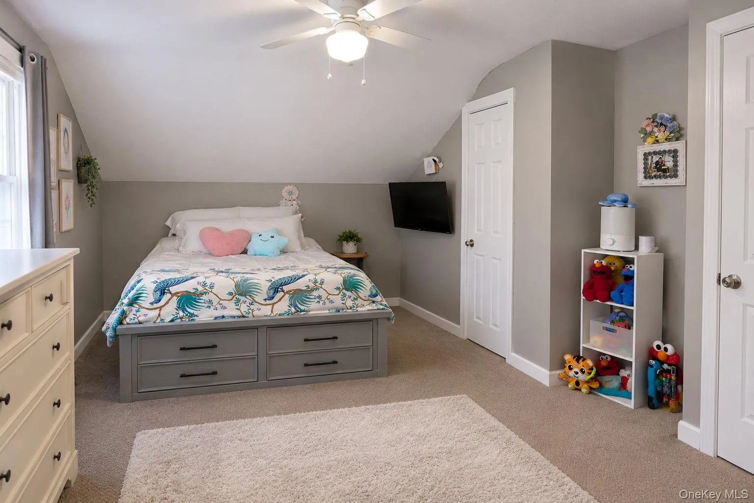 Neutral-toned bedroom featuring angled ceilings, neutral wall-to-wall carpeting, and a ceiling-mounted light fixture with integrated fan Neutral-toned bedroom featuring angled ceilings, neutral wall-to-wall carpeting, and a ceiling-mounted light fixture with integrated fan