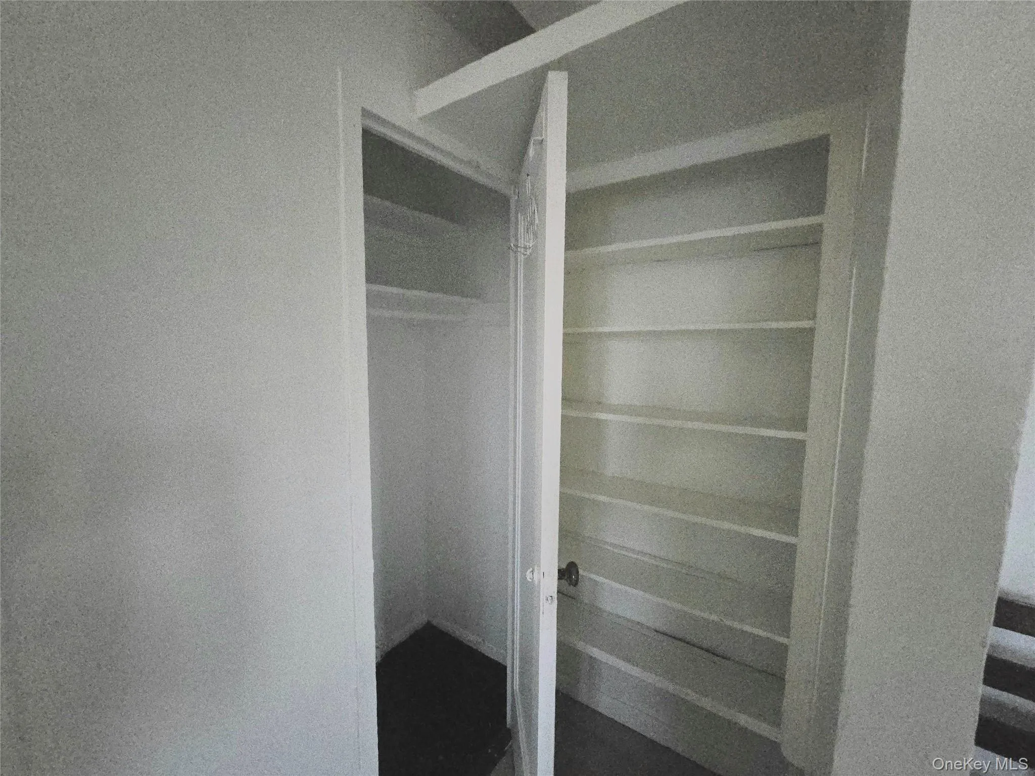 Storage area featuring a built-in closet with an overhead shelf and a separate recessed shelving unit with five fixed tiers Storage area featuring a built-in closet with an overhead shelf and a separate recessed shelving unit with five fixed tiers