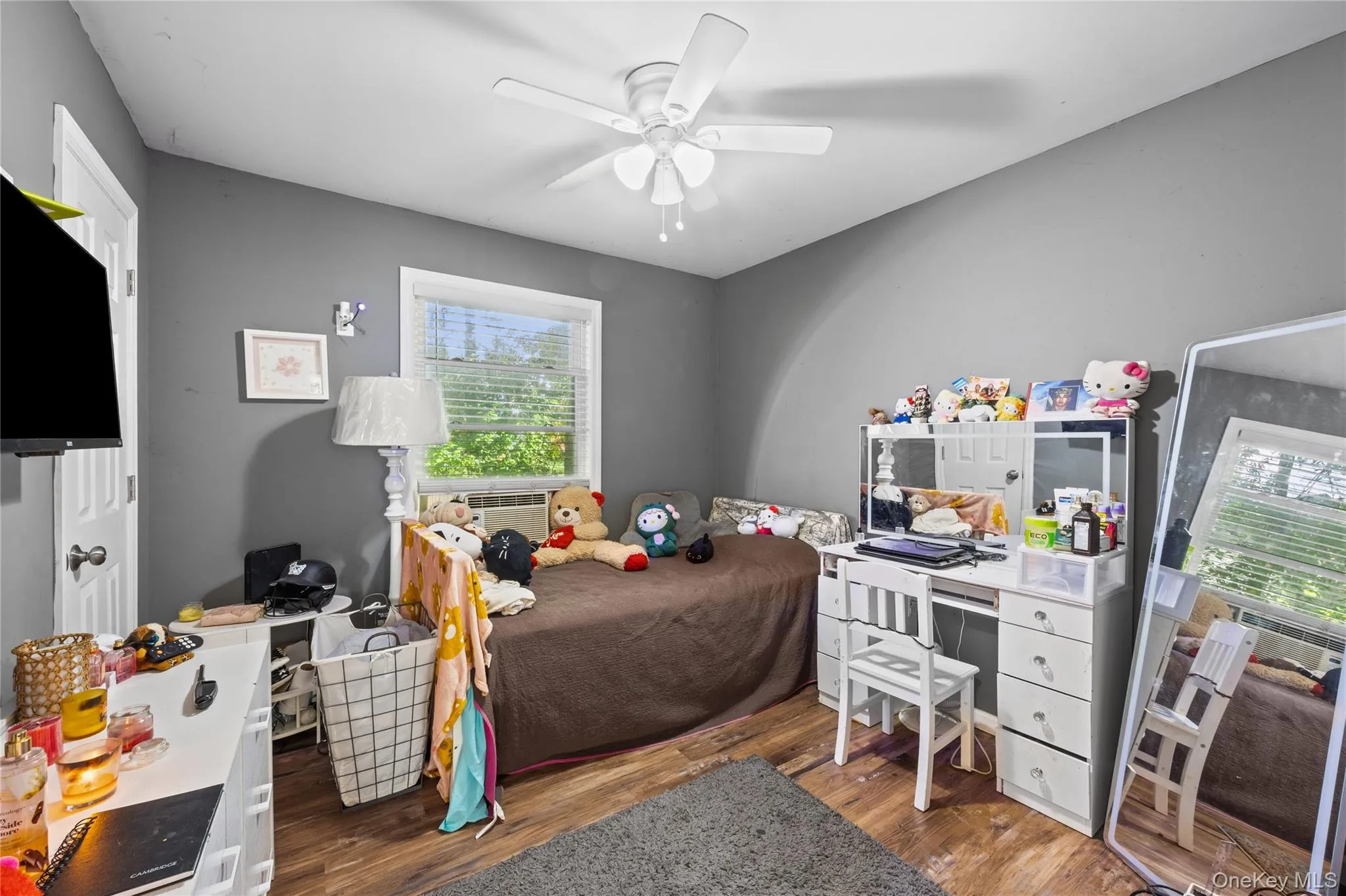 Room featuring wood-finish flooring, a ceiling fan with integrated lighting, and a window with blinds Room featuring wood-finish flooring, a ceiling fan with integrated lighting, and a window with blinds