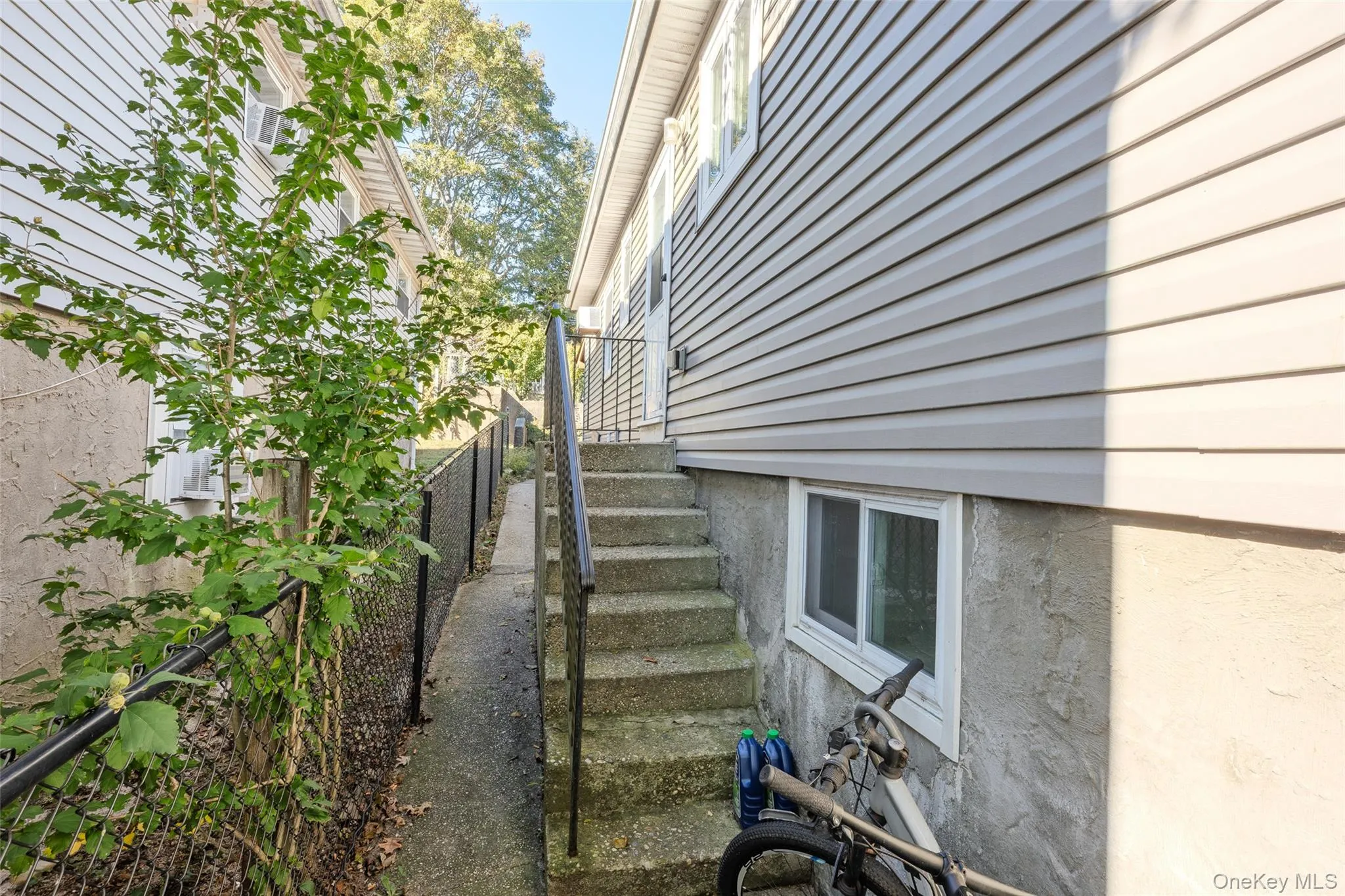 Exterior side entry featuring concrete stairs with a metal handrail, horizontal vinyl siding, and a concrete foundation Exterior side entry featuring concrete stairs with a metal handrail, horizontal vinyl siding, and a concrete foundation