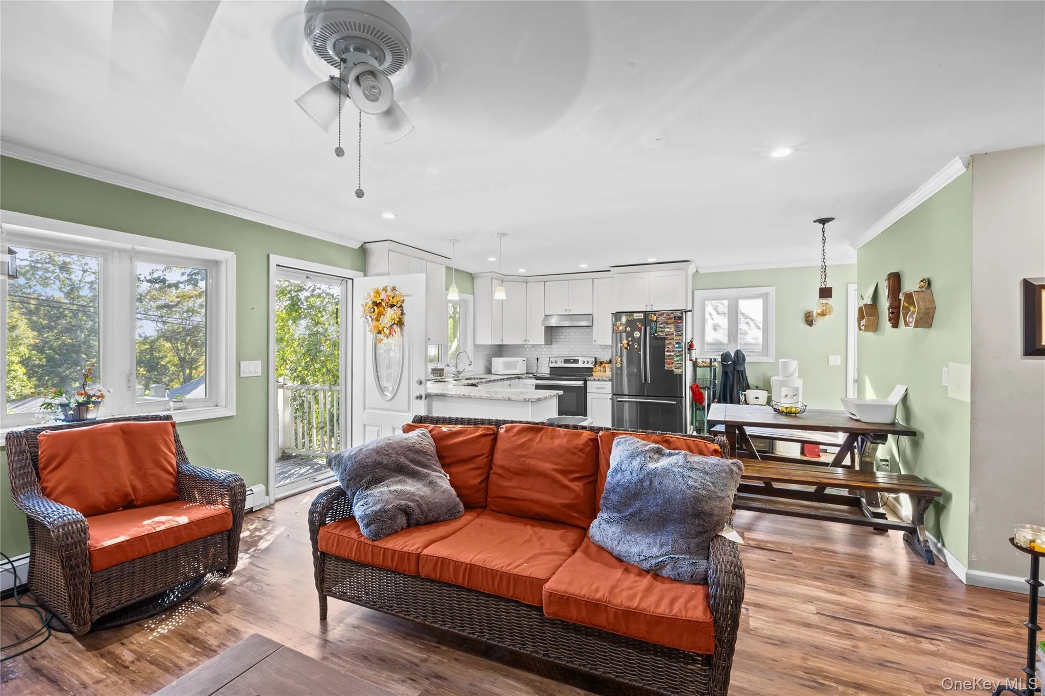Open-concept interior featuring wood-finish flooring, white cabinetry, a breakfast bar with stone-look countertops, and recessed lighting Open-concept interior featuring wood-finish flooring, white cabinetry, a breakfast bar with stone-look countertops, and recessed lighting