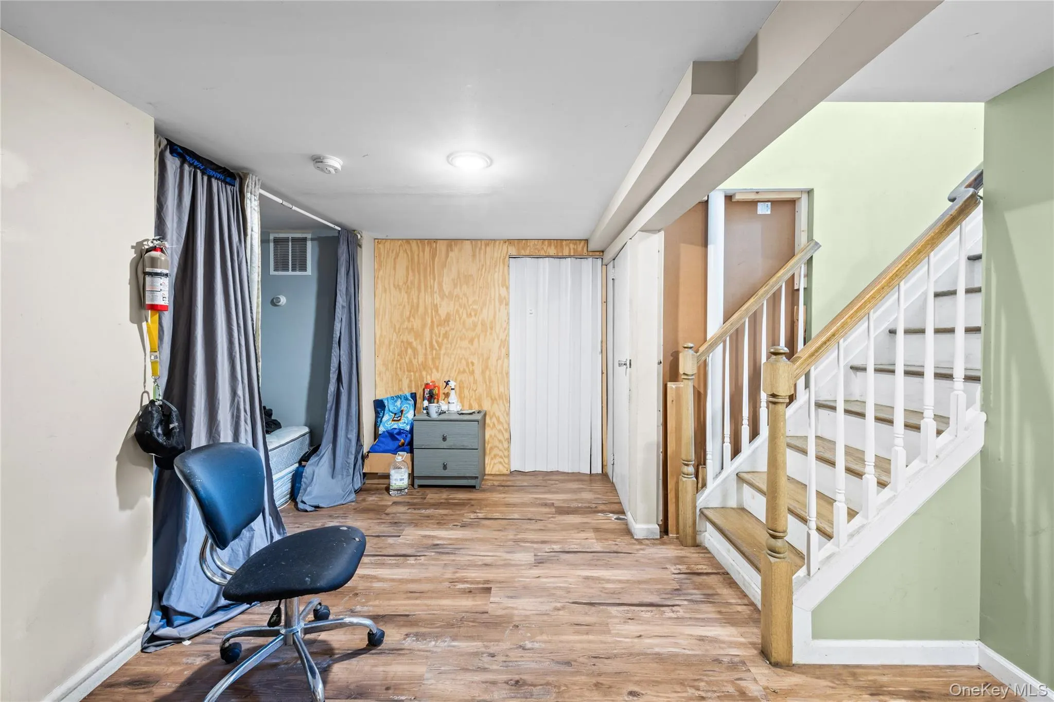 Interior space featuring wood-finish flooring, staircase with white balusters and wooden handrail, and built-in closet storage Interior space featuring wood-finish flooring, staircase with white balusters and wooden handrail, and built-in closet storage