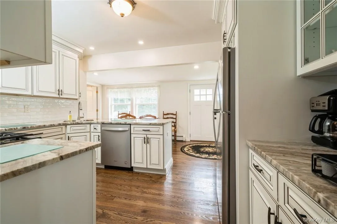 Kitchen featuring dark hardwood / wood-style floors, light stone counters, sink, kitchen peninsula, and stainless steel appliances Kitchen featuring dark hardwood / wood-style floors, light stone counters, sink, kitchen peninsula, and stainless steel appliances