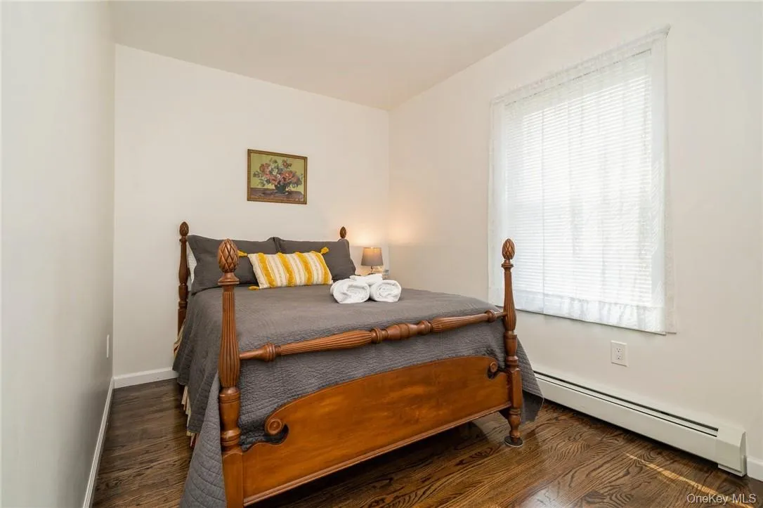 Bedroom featuring baseboard heating and dark hardwood / wood-style floors Bedroom featuring baseboard heating and dark hardwood / wood-style floors