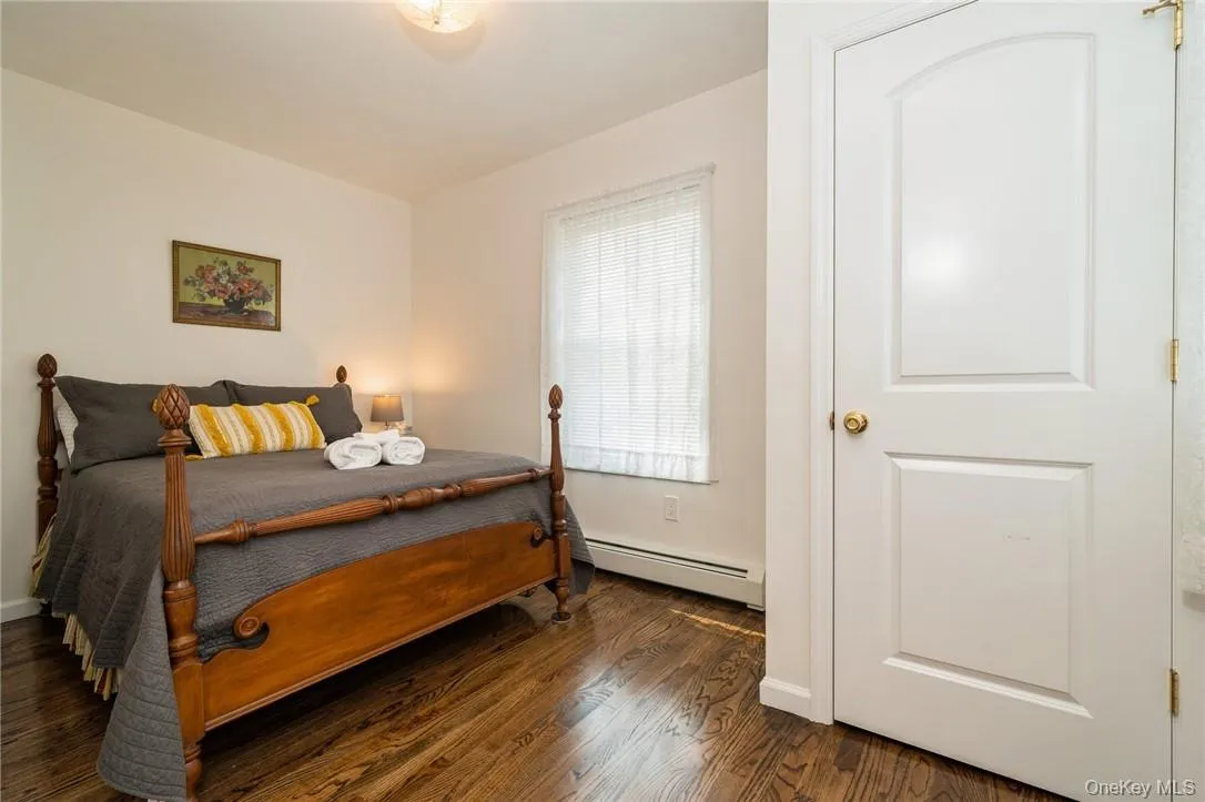 Bedroom with dark wood-type flooring and a baseboard heating unit Bedroom with dark wood-type flooring and a baseboard heating unit