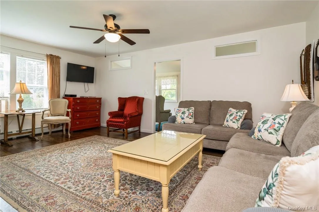 Living room with ceiling fan and dark wood-type flooring Living room with ceiling fan and dark wood-type flooring