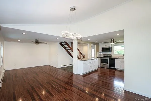 Unfurnished living room featuring ceiling fan, a chandelier, dark wood finished floors, stairway, and vaulted ceiling Unfurnished living room featuring ceiling fan, a chandelier, dark wood finished floors, stairway, and vaulted ceiling