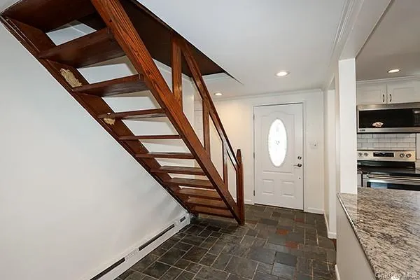 Foyer with baseboard heating, stone tile floors, stairway, recessed lighting, and ornamental molding Foyer with baseboard heating, stone tile floors, stairway, recessed lighting, and ornamental molding