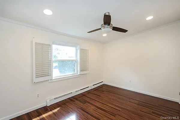 Empty room with a baseboard heating unit, dark wood-type flooring, crown molding, recessed lighting, and a ceiling fan Empty room with a baseboard heating unit, dark wood-type flooring, crown molding, recessed lighting, and a ceiling fan