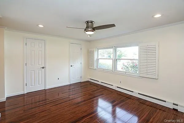 Unfurnished bedroom featuring a baseboard heating unit, ornamental molding, recessed lighting, dark wood-style floors, and a ceiling fan Unfurnished bedroom featuring a baseboard heating unit, ornamental molding, recessed lighting, dark wood-style floors, and a ceiling fan