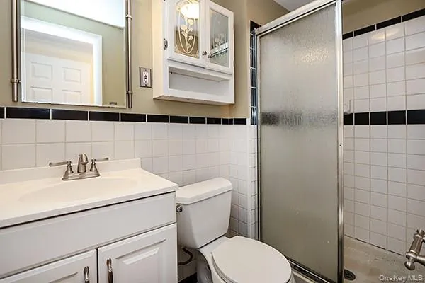 Full bathroom featuring a shower stall, vanity, and tile walls Full bathroom featuring a shower stall, vanity, and tile walls