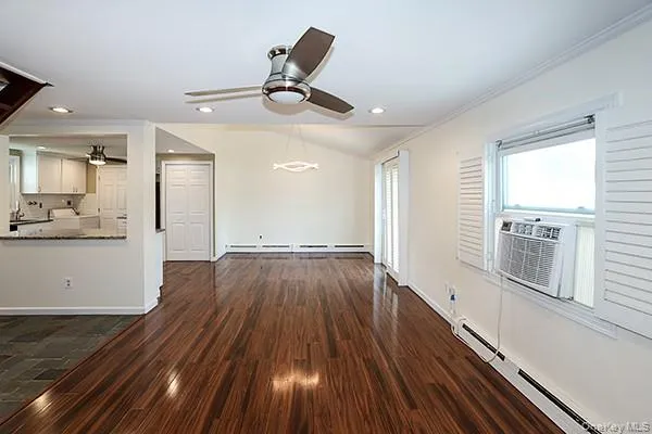 Unfurnished living room featuring a baseboard radiator, dark wood-type flooring, a ceiling fan, recessed lighting, and vaulted ceiling Unfurnished living room featuring a baseboard radiator, dark wood-type flooring, a ceiling fan, recessed lighting, and vaulted ceiling