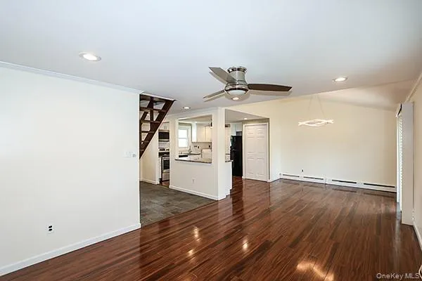 Unfurnished living room featuring dark wood-style floors, a baseboard heating unit, recessed lighting, a ceiling fan, and ornamental molding Unfurnished living room featuring dark wood-style floors, a baseboard heating unit, recessed lighting, a ceiling fan, and ornamental molding