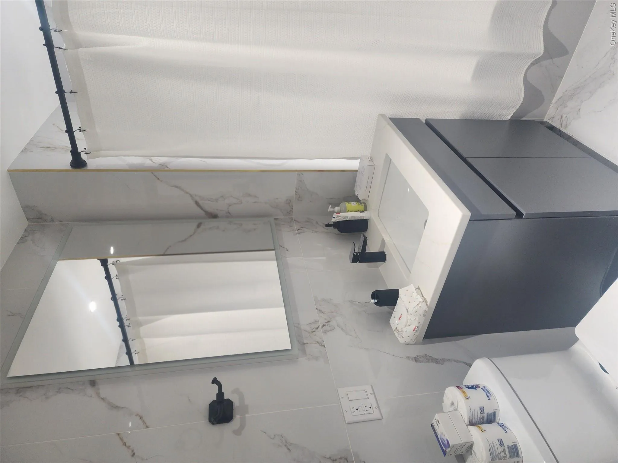 Modern vanity with a rectangular basin, light-toned countertop, and matte black hardware, accented by large-format wall tiling and a rectangular wall-mounted mirror Modern vanity with a rectangular basin, light-toned countertop, and matte black hardware, accented by large-format wall tiling and a rectangular wall-mounted mirror