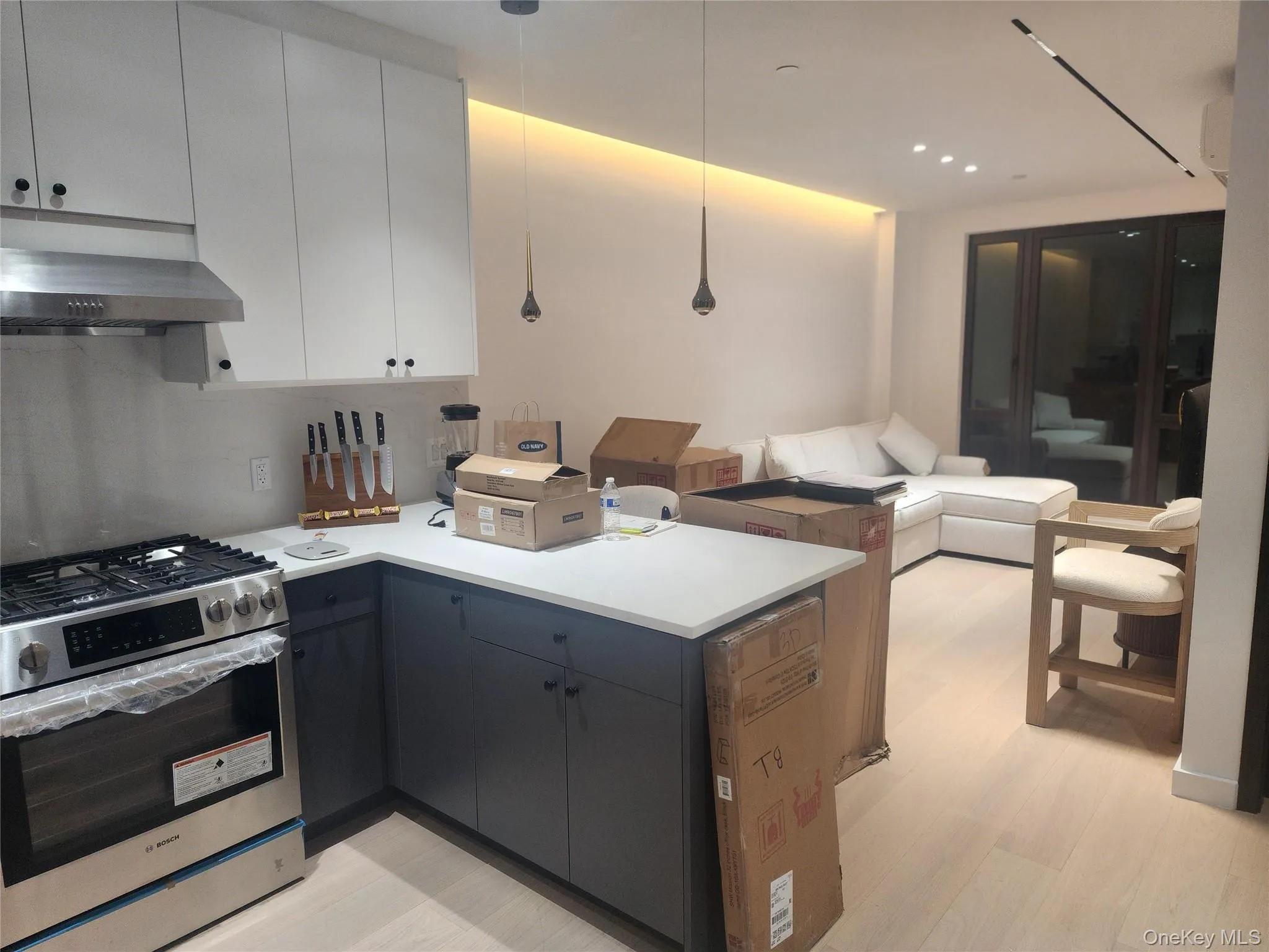 Two-tone cabinetry featuring white upper cabinets and charcoal lower cabinets with quartz countertops, wood-finish flooring, stainless steel gas range, and recessed ceiling lighting Two-tone cabinetry featuring white upper cabinets and charcoal lower cabinets with quartz countertops, wood-finish flooring, stainless steel gas range, and recessed ceiling lighting