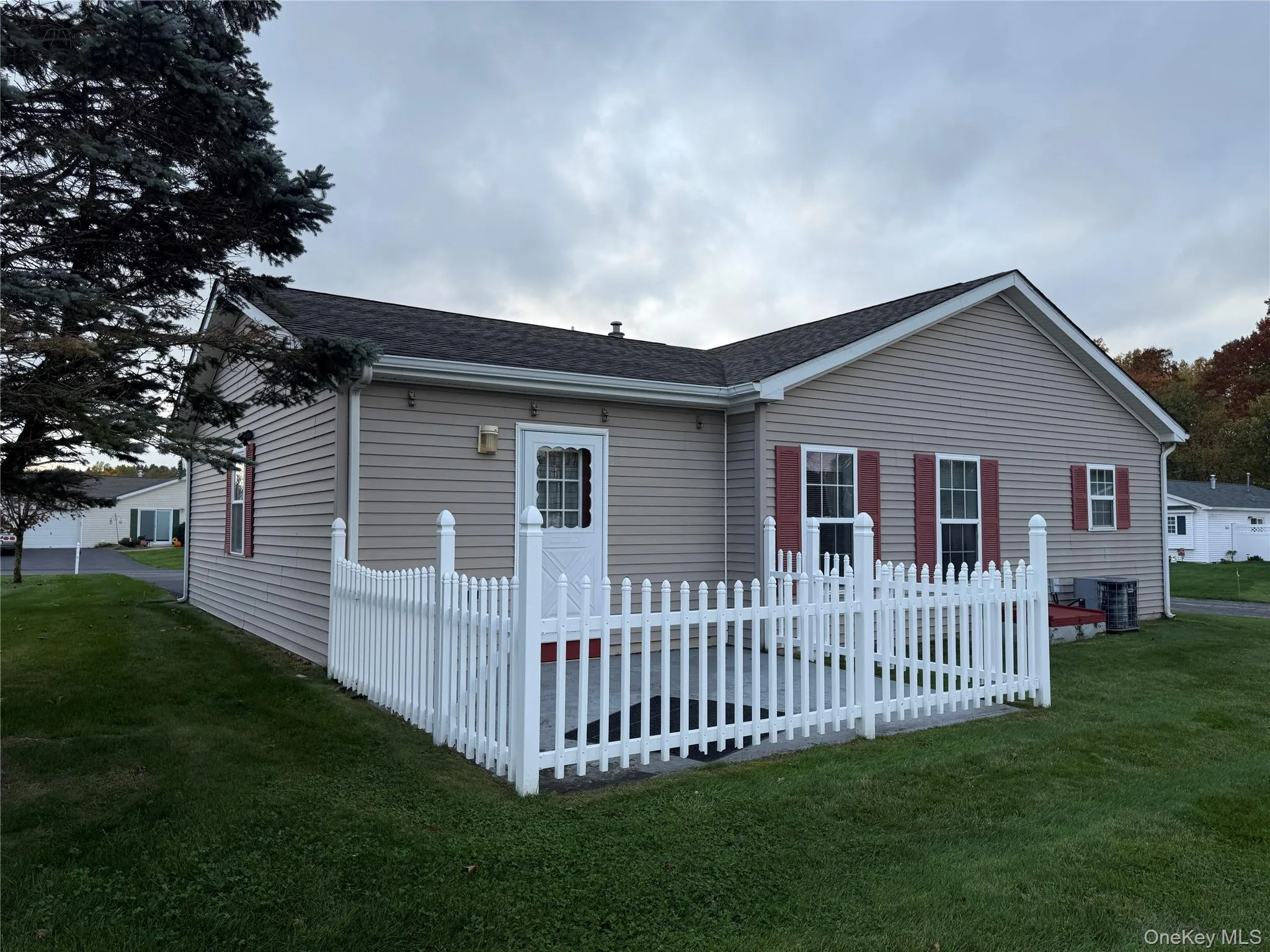 Single-story home featuring light-toned horizontal siding, a fenced-in concrete patio, and decorative window shutters Single-story home featuring light-toned horizontal siding, a fenced-in concrete patio, and decorative window shutters