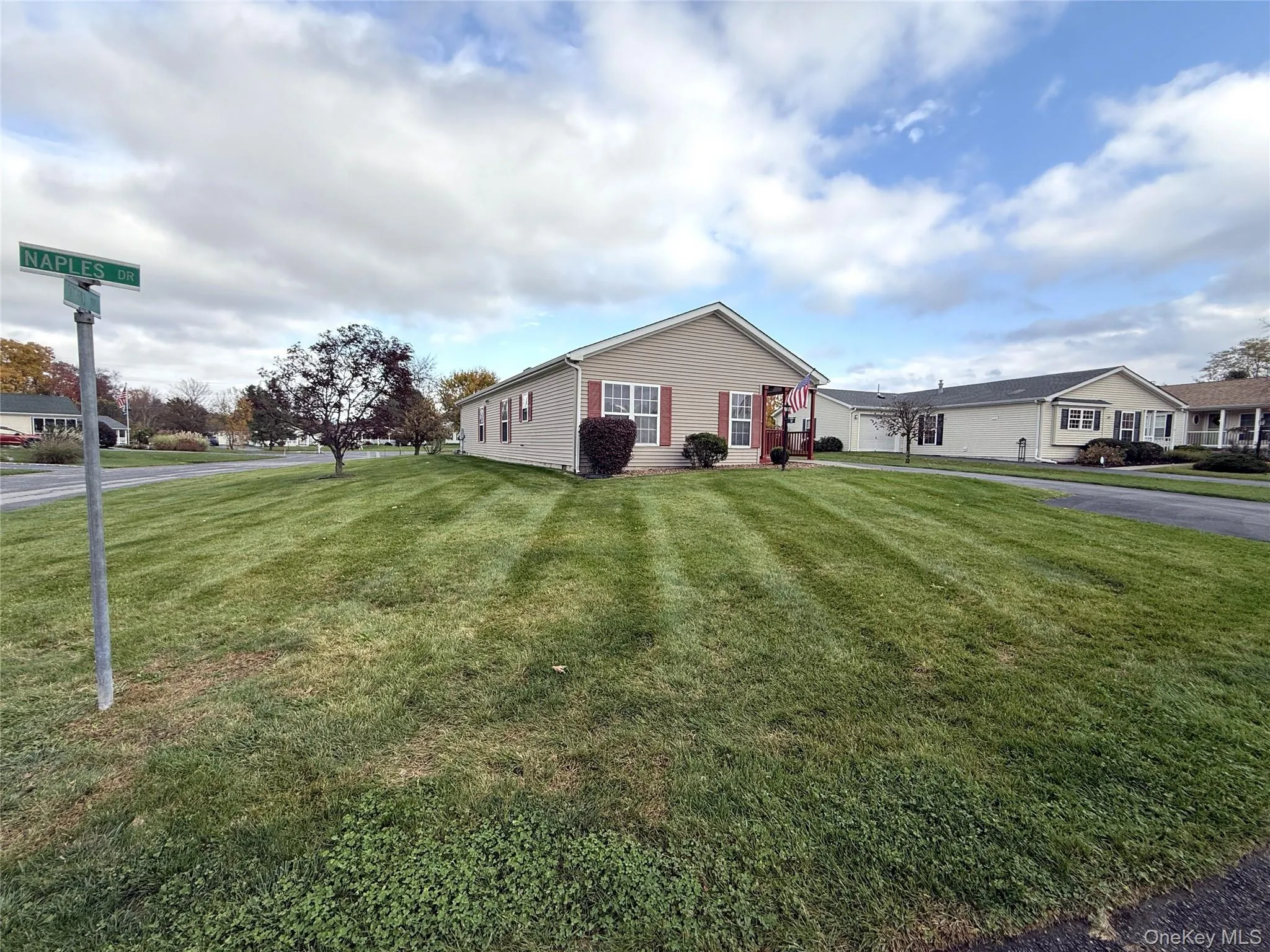 Single-story residence featuring light-toned vinyl siding, contrasting shutters, a gabled roofline, and an expansive lawn situated on a corner lot Single-story residence featuring light-toned vinyl siding, contrasting shutters, a gabled roofline, and an expansive lawn situated on a corner lot