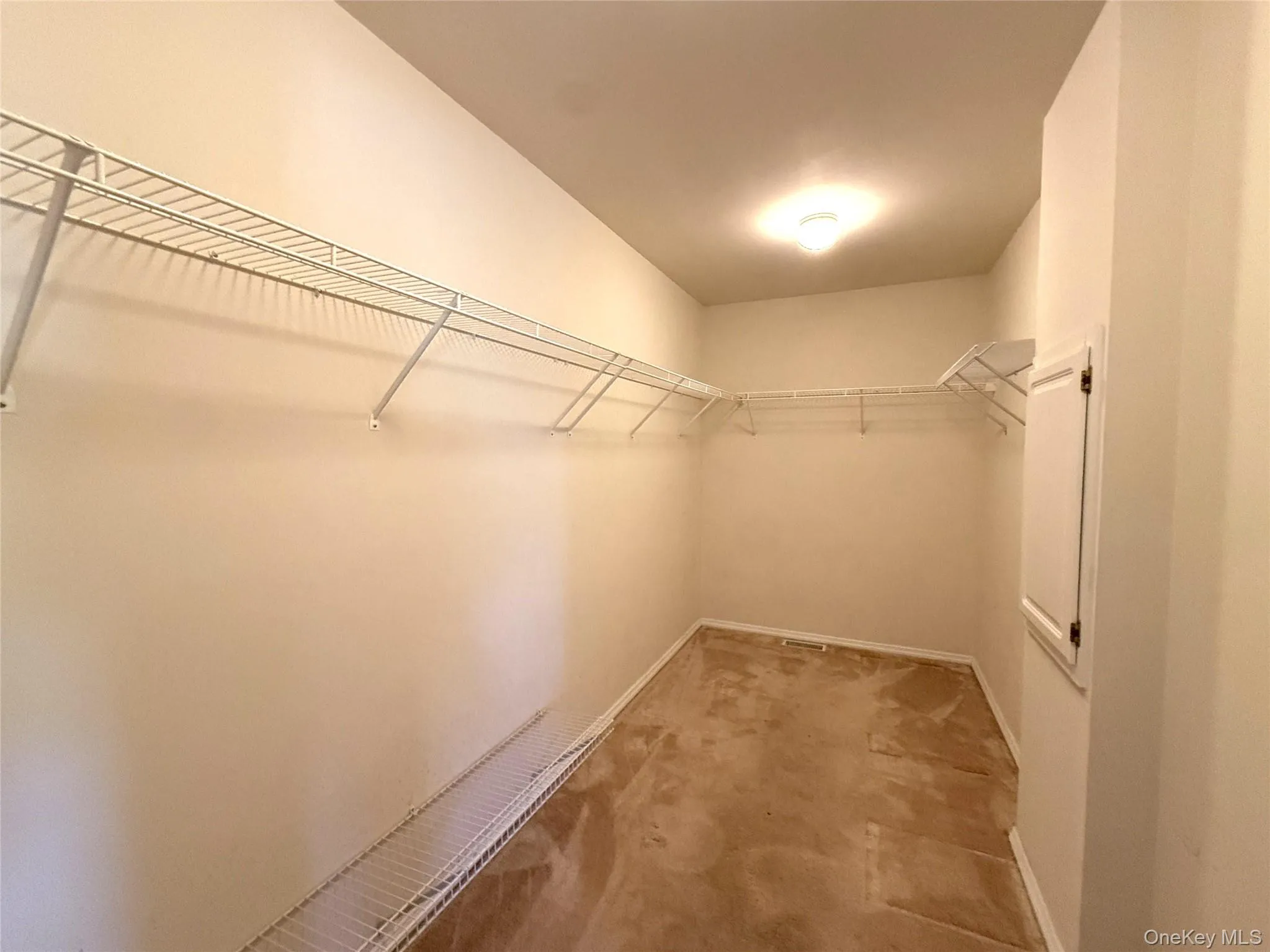 Walk-in closet featuring wraparound white wire shelving, and neutral carpeting. Walk-in closet featuring wraparound white wire shelving, and neutral carpeting.