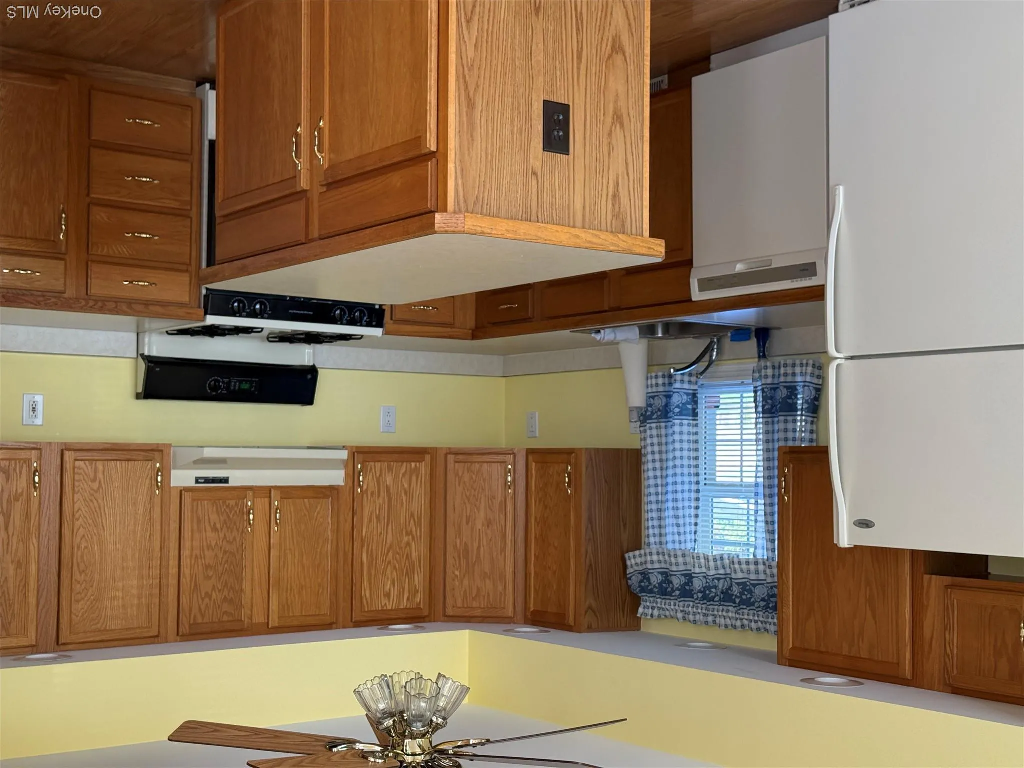 Kitchen featuring wood cabinetry, central island, wood-finish flooring, and integrated white appliances Kitchen featuring wood cabinetry, central island, wood-finish flooring, and integrated white appliances
