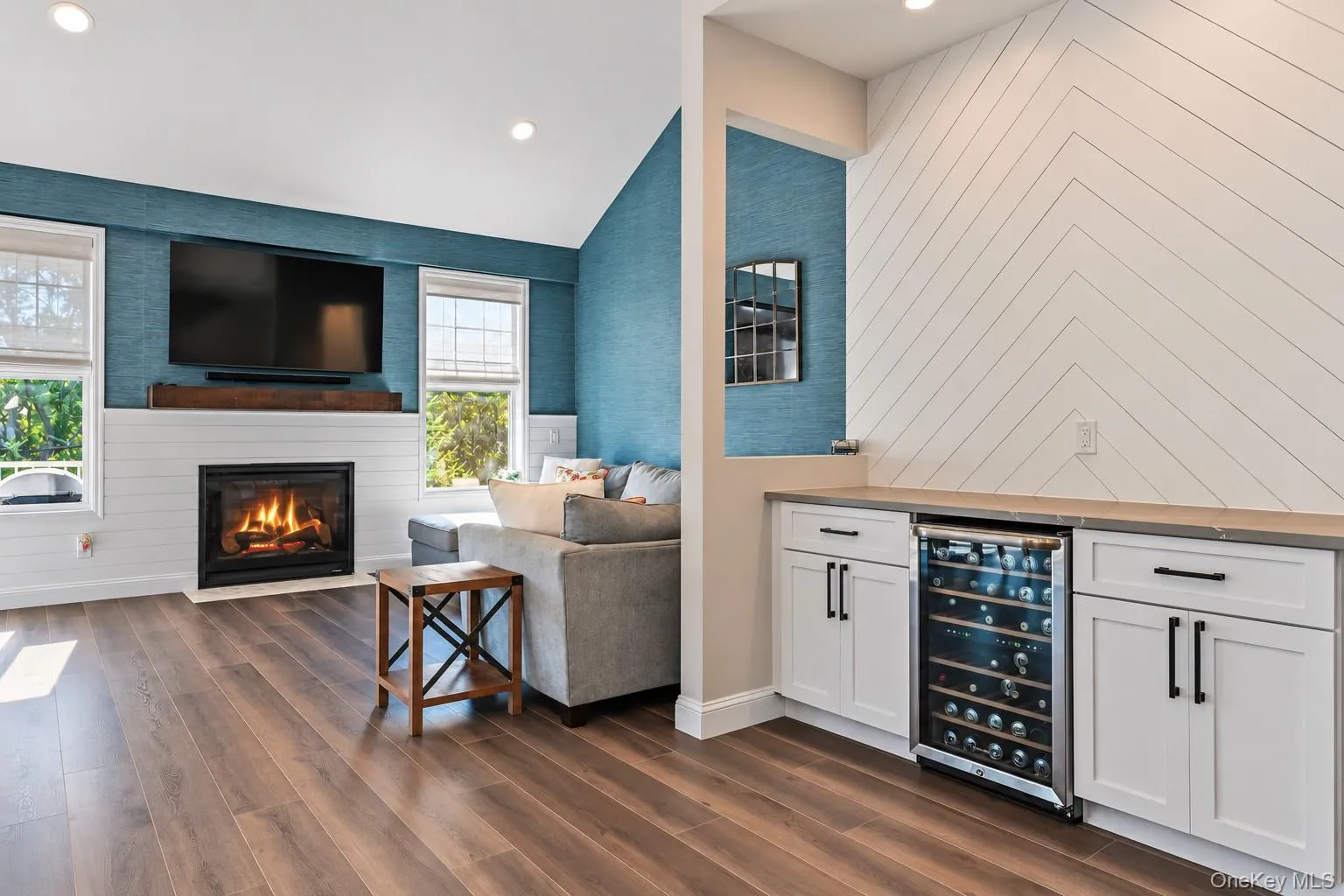 Vaulted ceilings, gas fireplace with wood mantel, built-in beverage refrigerator, and white cabinetry with matte black hardware Vaulted ceilings, gas fireplace with wood mantel, built-in beverage refrigerator, and white cabinetry with matte black hardware